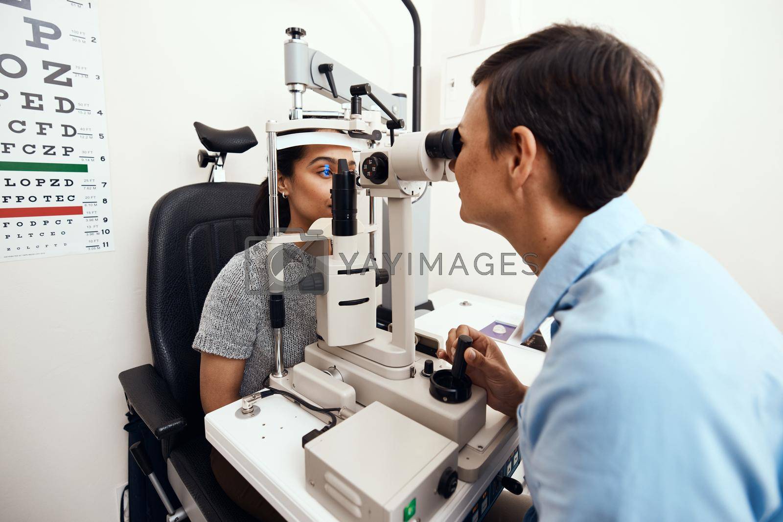 Royalty free image of Eye and vision test, exam or screening with an optometrist, optician or ophthalmologist and a patient using an ophthalmoscope. Testing and checking eyesight for prescription glasses or contact lenses by YuriArcurs
