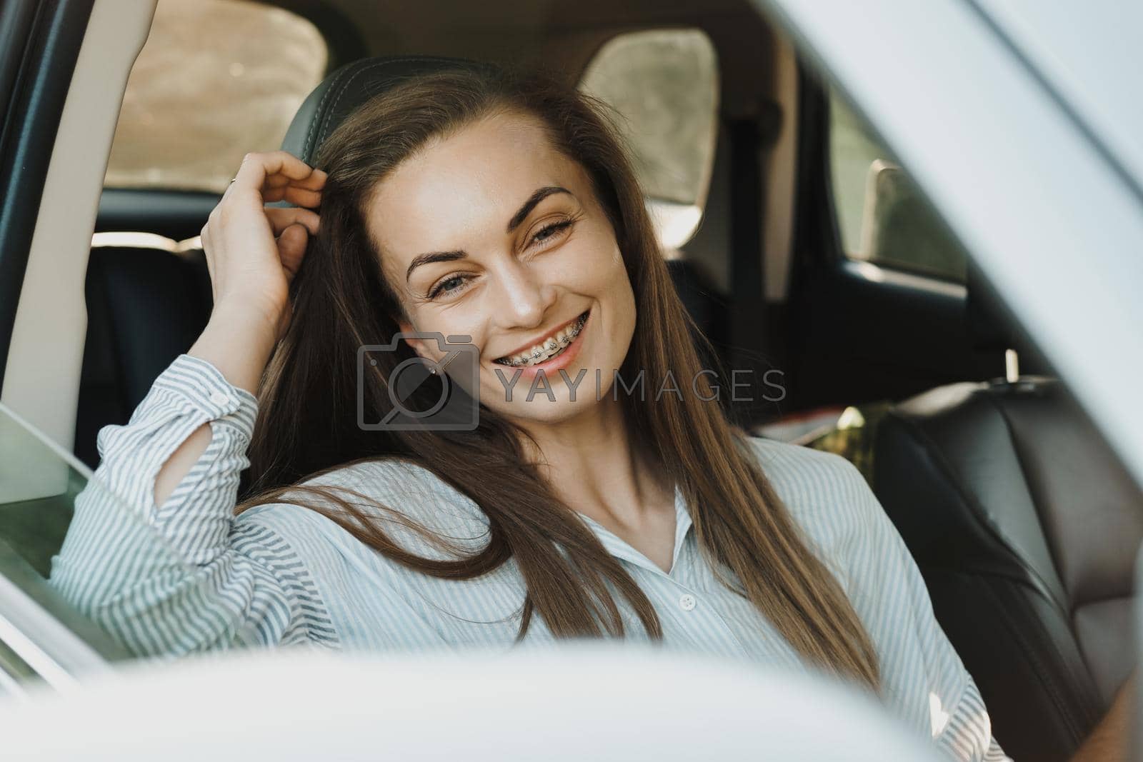 Royalty free image of Middle aged woman with dental braces smile while sitting inside car by Romvy