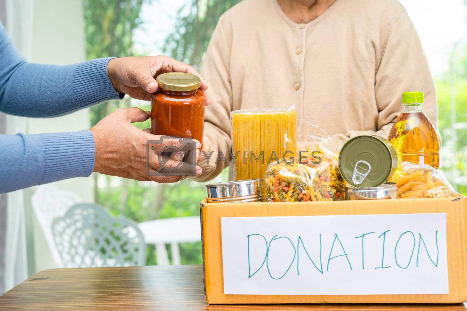 Royalty free image of Volunteers putting various dry food in donation box for help people. by pamai