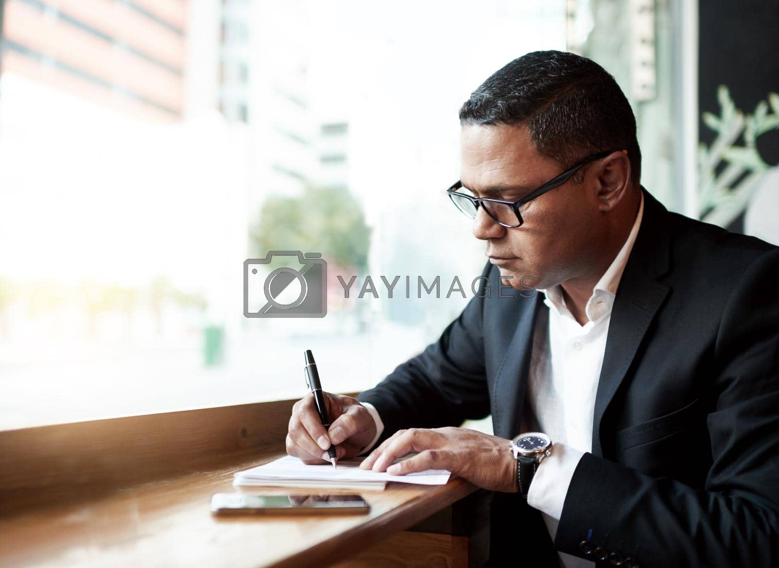 Royalty free image of The office isnt the only place he does business. a handsome mature businessman doing some work while sitting in a coffee shop. by YuriArcurs