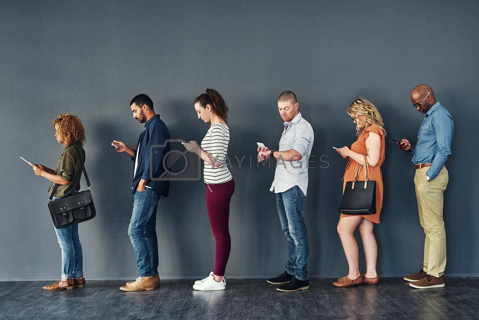 Royalty free image of Connected in their own ways. Studio shot of people waiting in line against a grey background. by YuriArcurs
