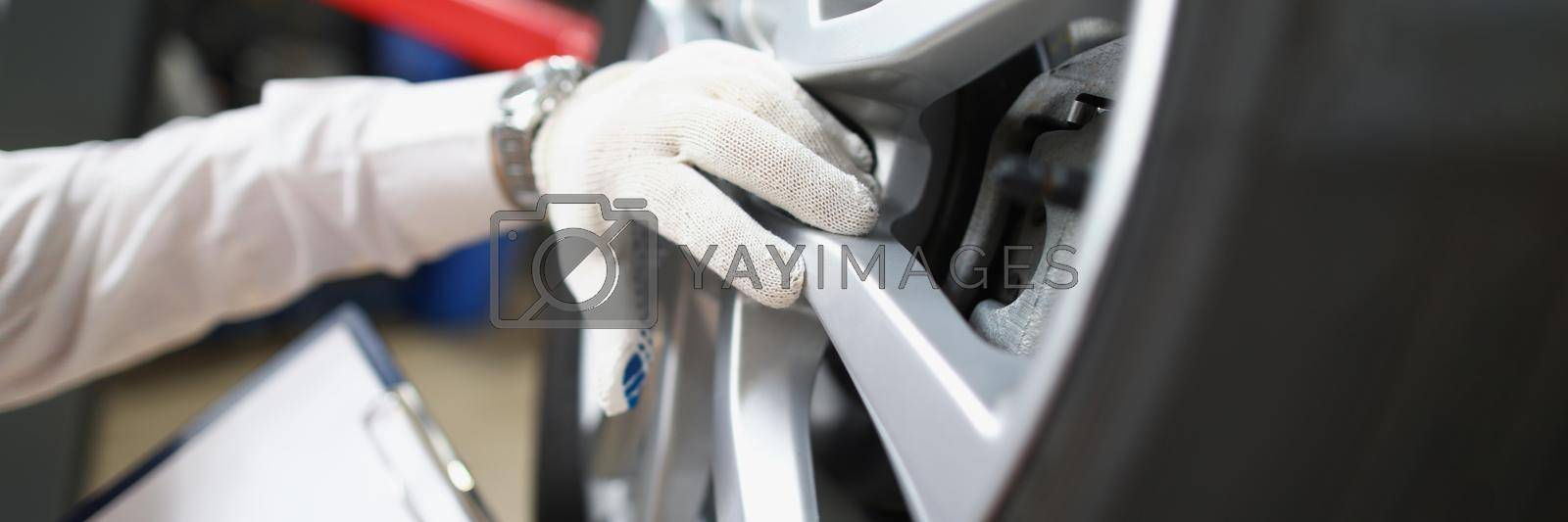 Royalty free image of Master repairman holding documents and looking at quality of tires closeup by kuprevich