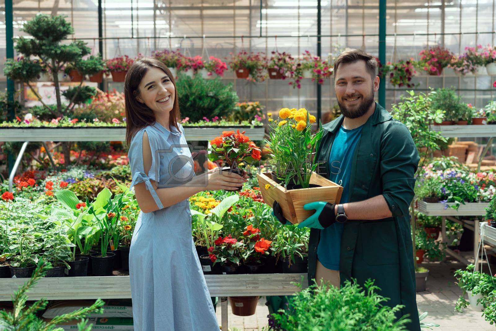Royalty free image of Worker helping female customer to buy flowers in garden center by Mariakray