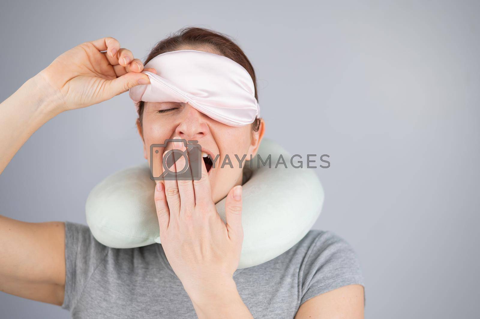 Royalty free image of Caucasian woman yawns with travel pillow and sleep mask on white background. by mrwed54