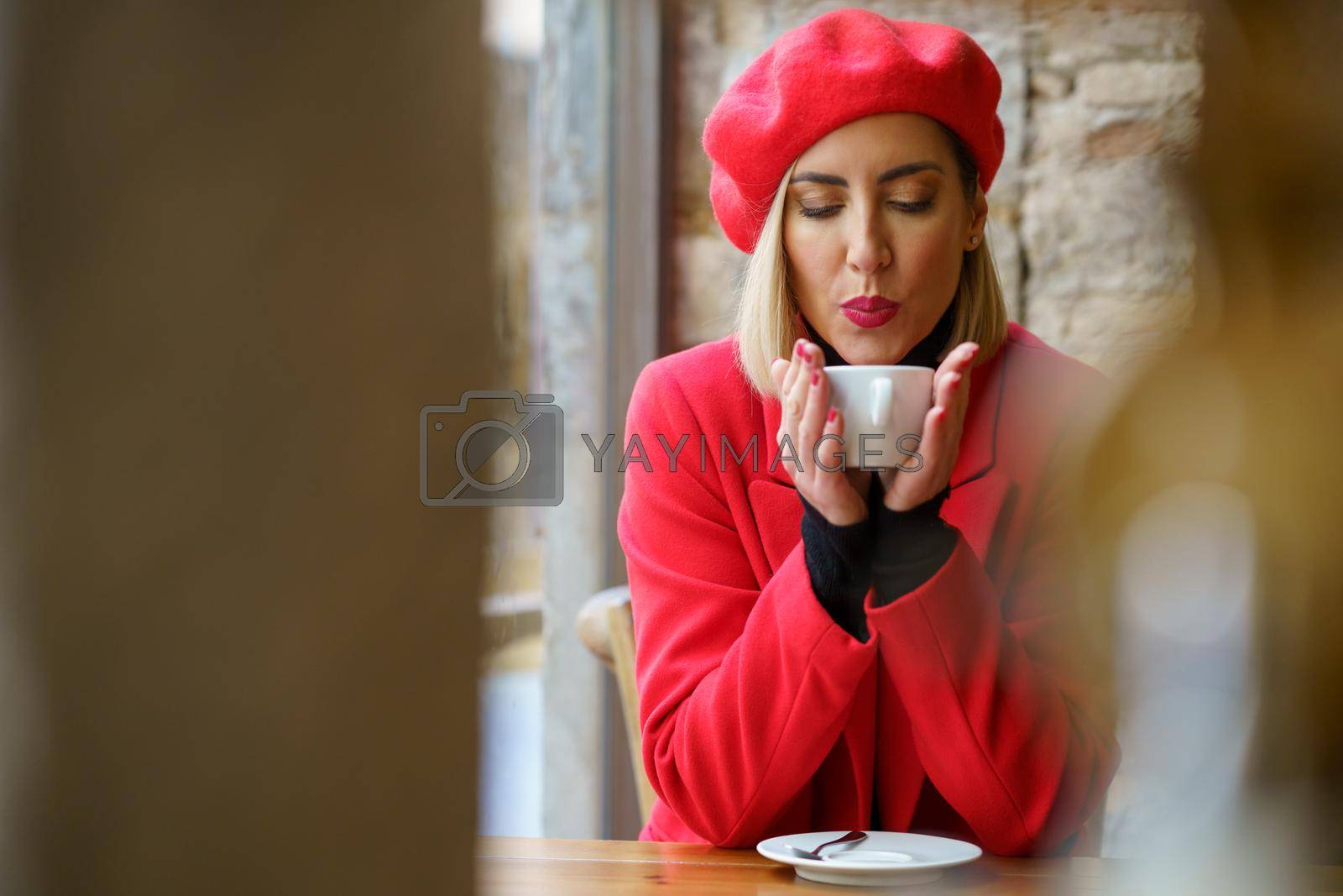 Royalty free image of Woman blowing on hot coffee in cafe by javiindy