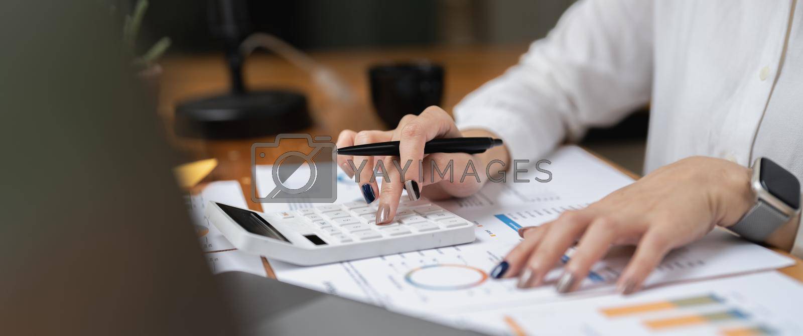 Royalty free image of Woman accountant using calculator and computer in office panoramic banner, finance and accounting concept by nateemee