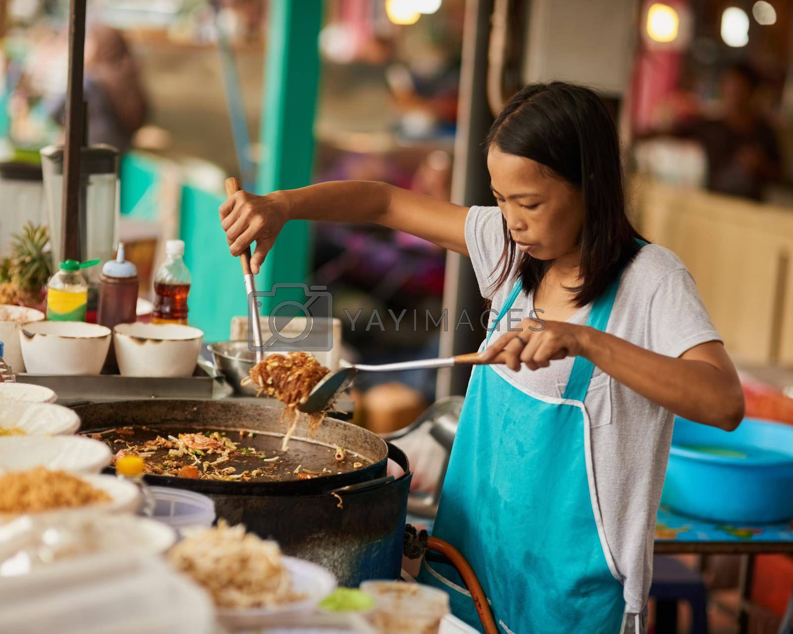Whos hungry. a food vendor preparing a Thai dish at a food market