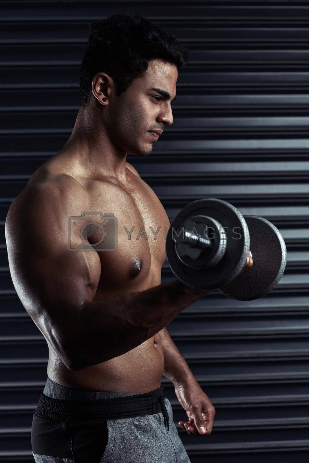Royalty free image of Biceps built for curling. an athletic young man working out with a dumbbell. by YuriArcurs