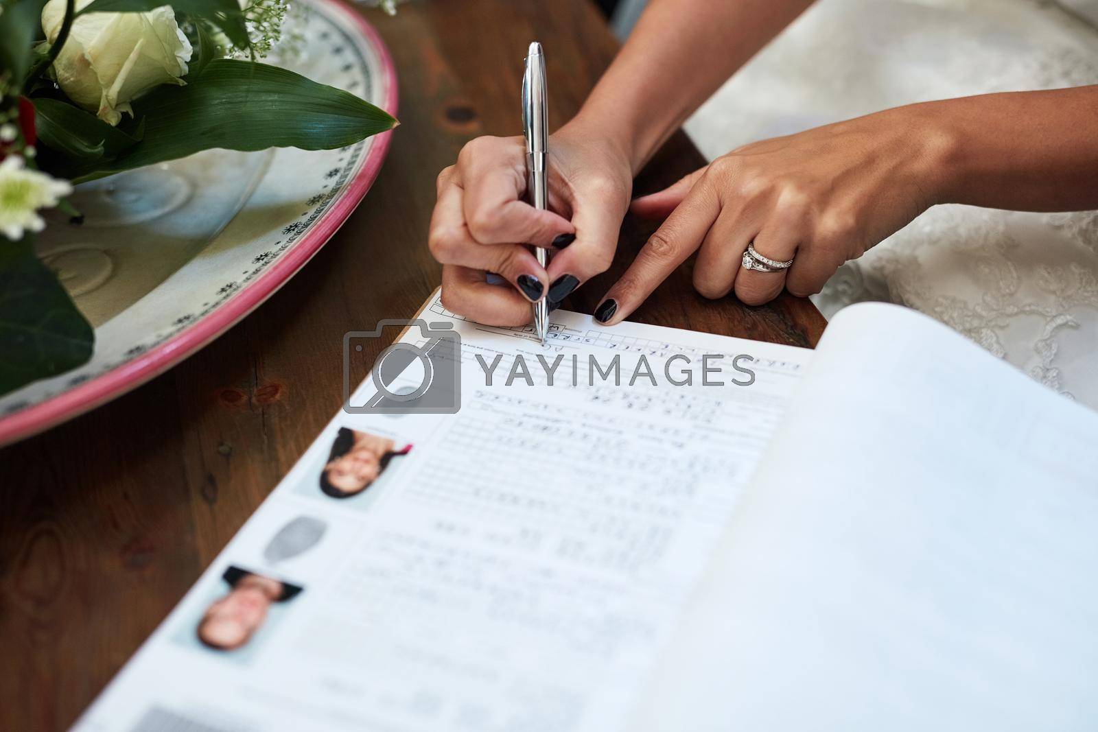 Royalty free image of Making it official. an unrecognisable bride signing paperwork on her wedding day. by YuriArcurs