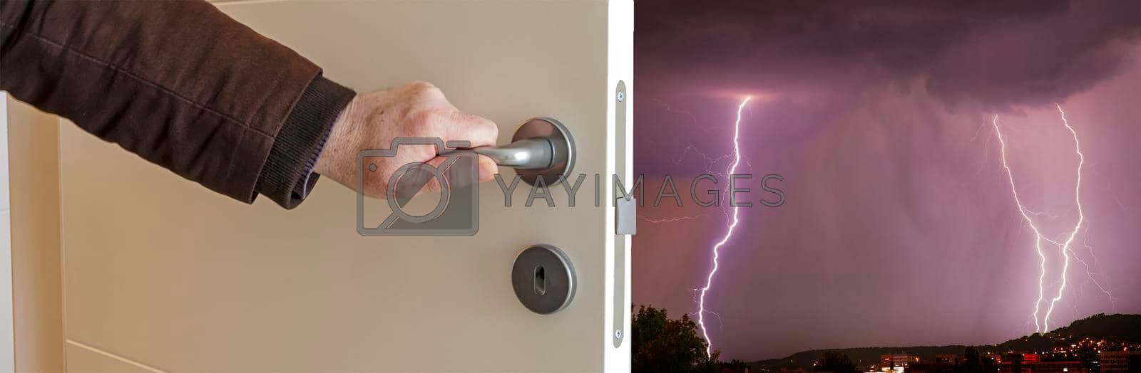 Royalty free image of Close-up view of male hand opening door to thunderstorm with flash. Banner view by EdVal