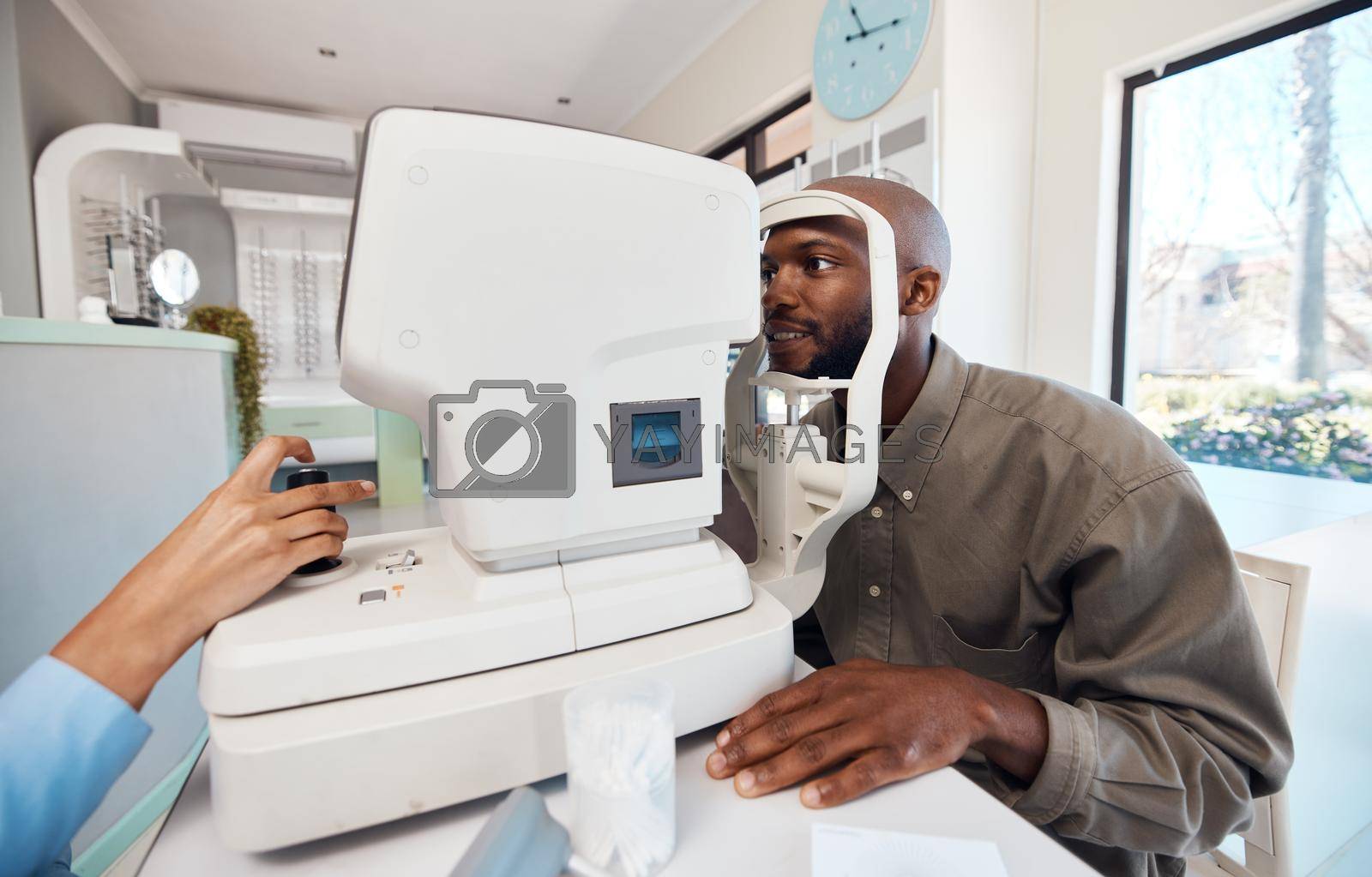 Royalty free image of Eye test, exam or screening with a young man at the optometrist using an automated refractor. Patient testing his vision and eyesight with an optician for prescription glasses or contact lenses by YuriArcurs