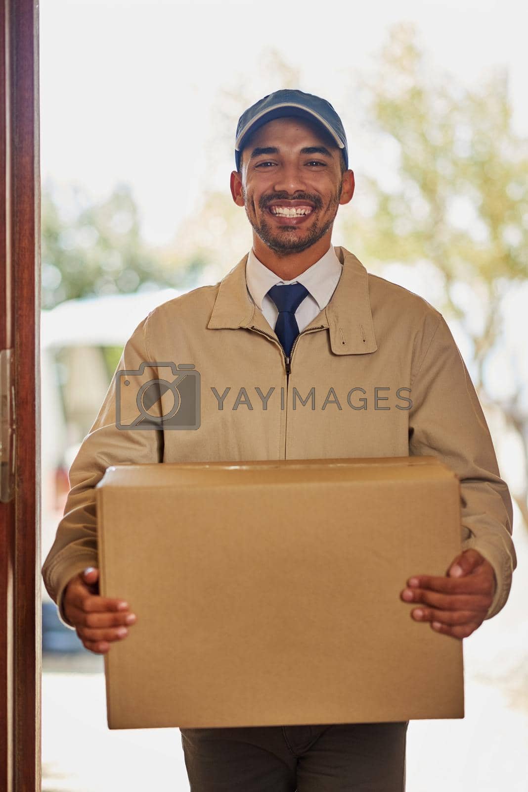 Royalty free image of Your package has arrived. Portrait of a friendly delivery man delivering a box to a customers door. by YuriArcurs