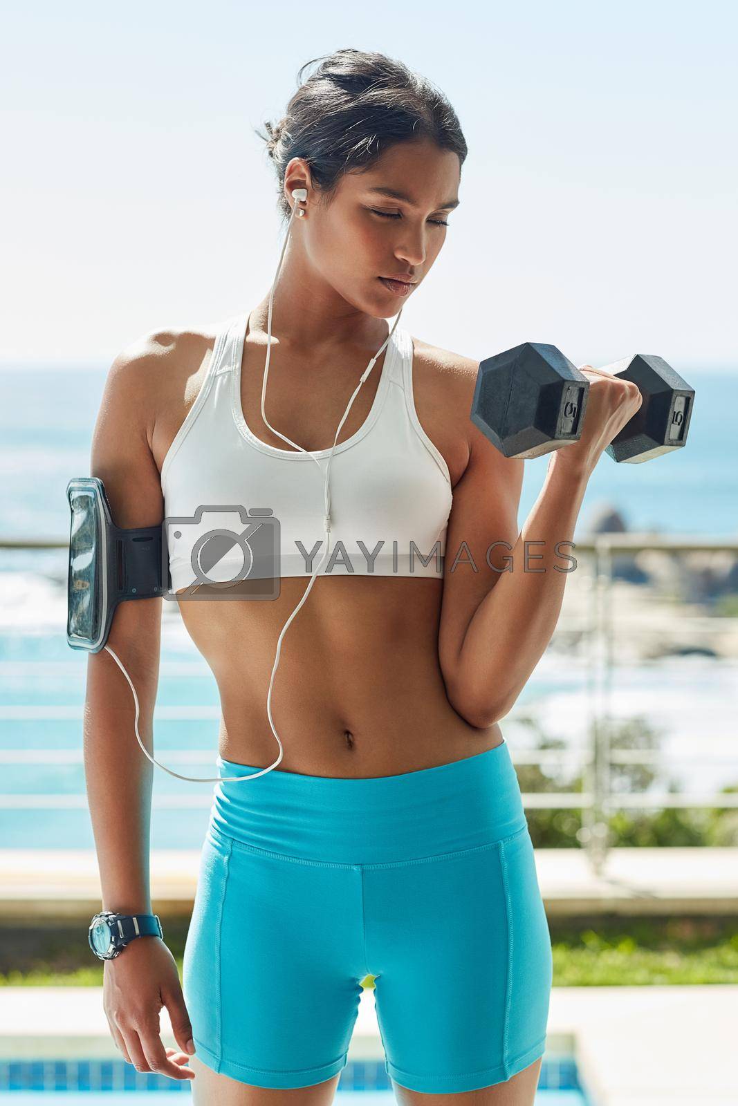 Royalty free image of Do it for the body you always wanted. a young woman using dumbbells in her workout routine. by YuriArcurs