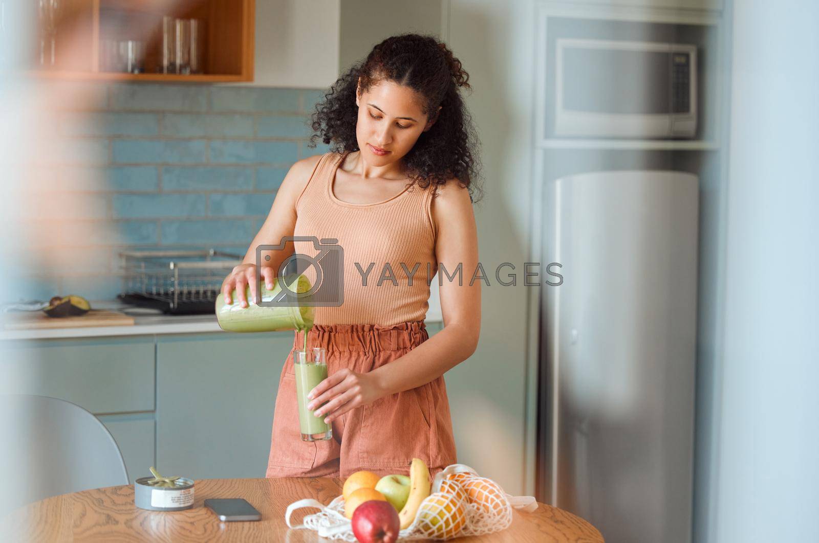 Royalty free image of Healthy, nutrition and wellness smoothie made by young woman for her fresh, green detox or vegan diet at home in her kitchen. Vegetarian female pouring and drinking her organic homemade fruit juice by YuriArcurs