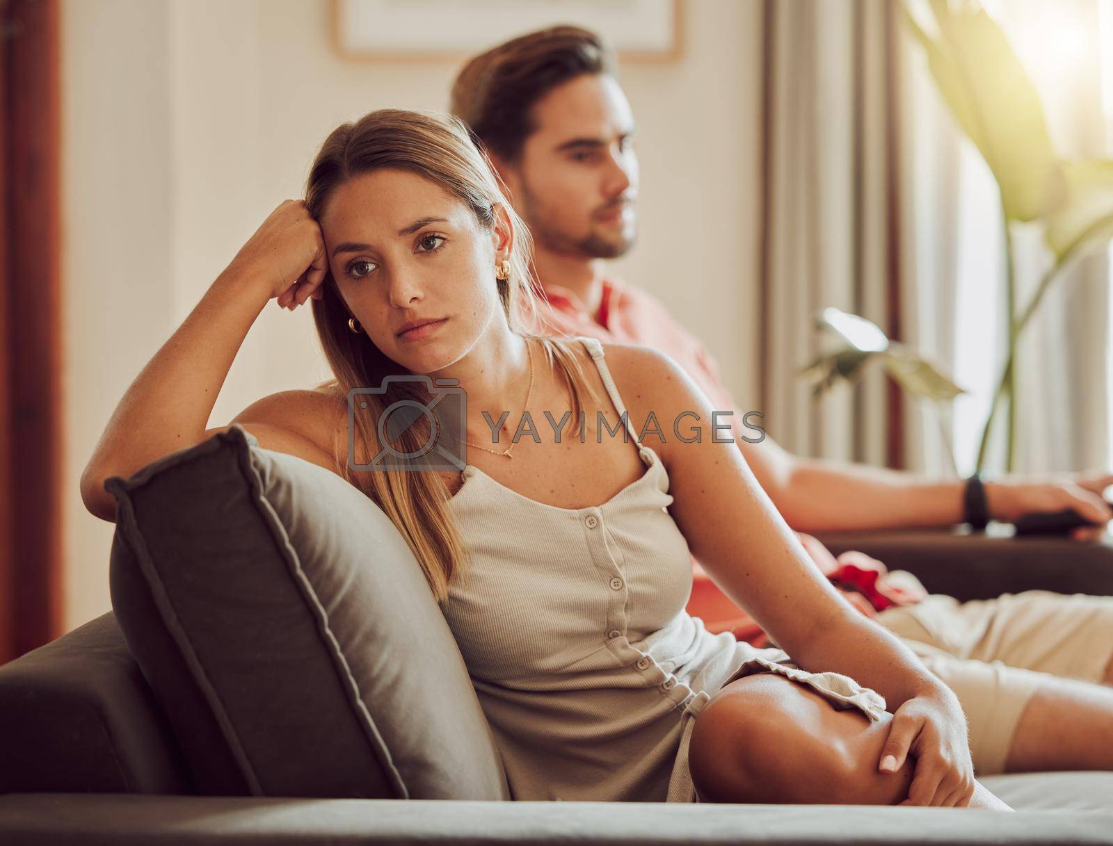 Royalty free image of Unhappy, sad and annoyed couple after a fight and are angry at each other while sitting on a couch at home. A woman is stressed, upset and frustrated by her boyfriend after an argument by YuriArcurs