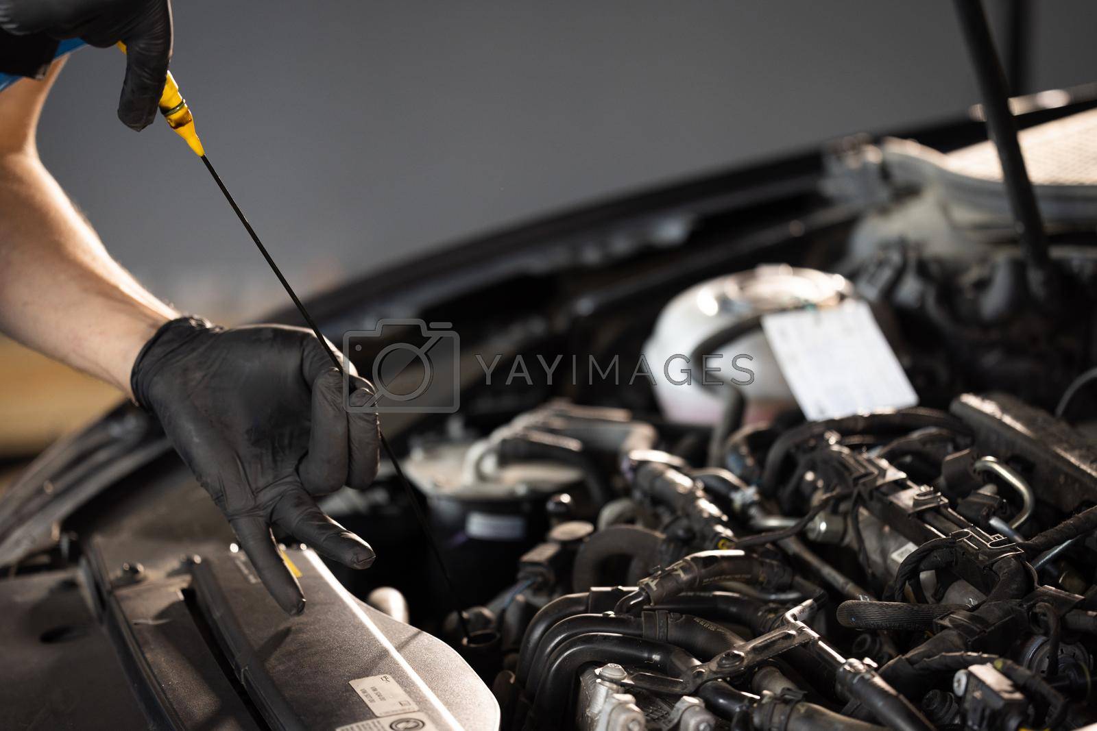 Royalty free image of The car mechanic is checking the engine oil level. Overheating of car engine. Motor with open hood. Checking the engine oil car maintenance Remove the dipstick to view the engine oil level by uflypro