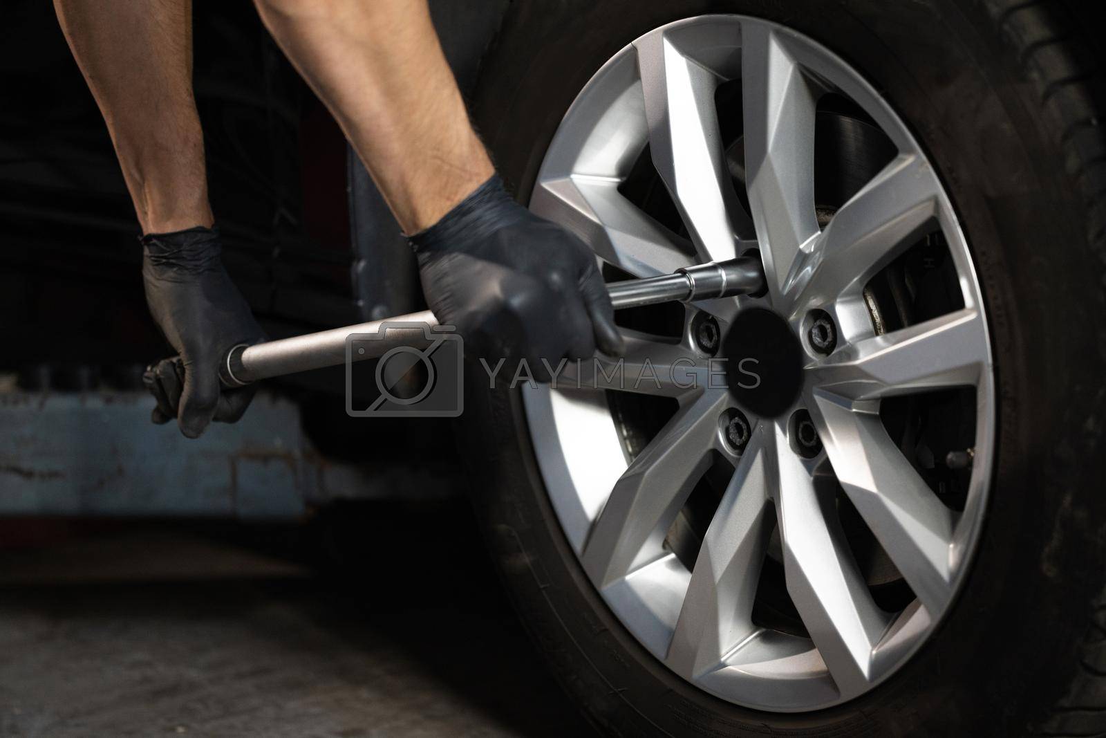 Royalty free image of Car mechanic replacing a car wheel tire in garage workshop. Auto service. Repairman mounting wheel tire at service station by uflypro