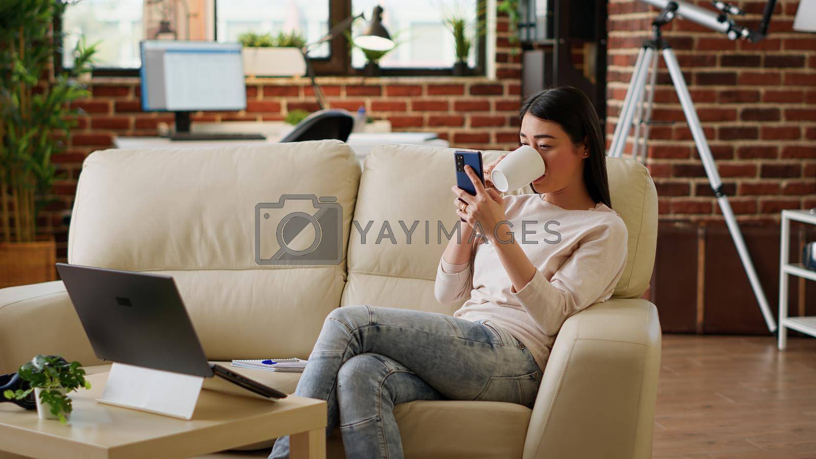 Royalty free image of Happy woman sending messages on mobile phone while doing work from home by DCStudio