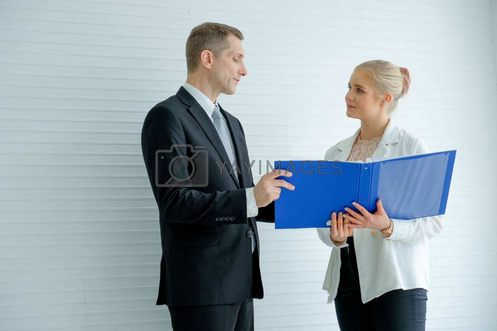 Royalty free image of The manager man discuss with young secretary woman who hold blue file folder with white pattern background. by nrradmin