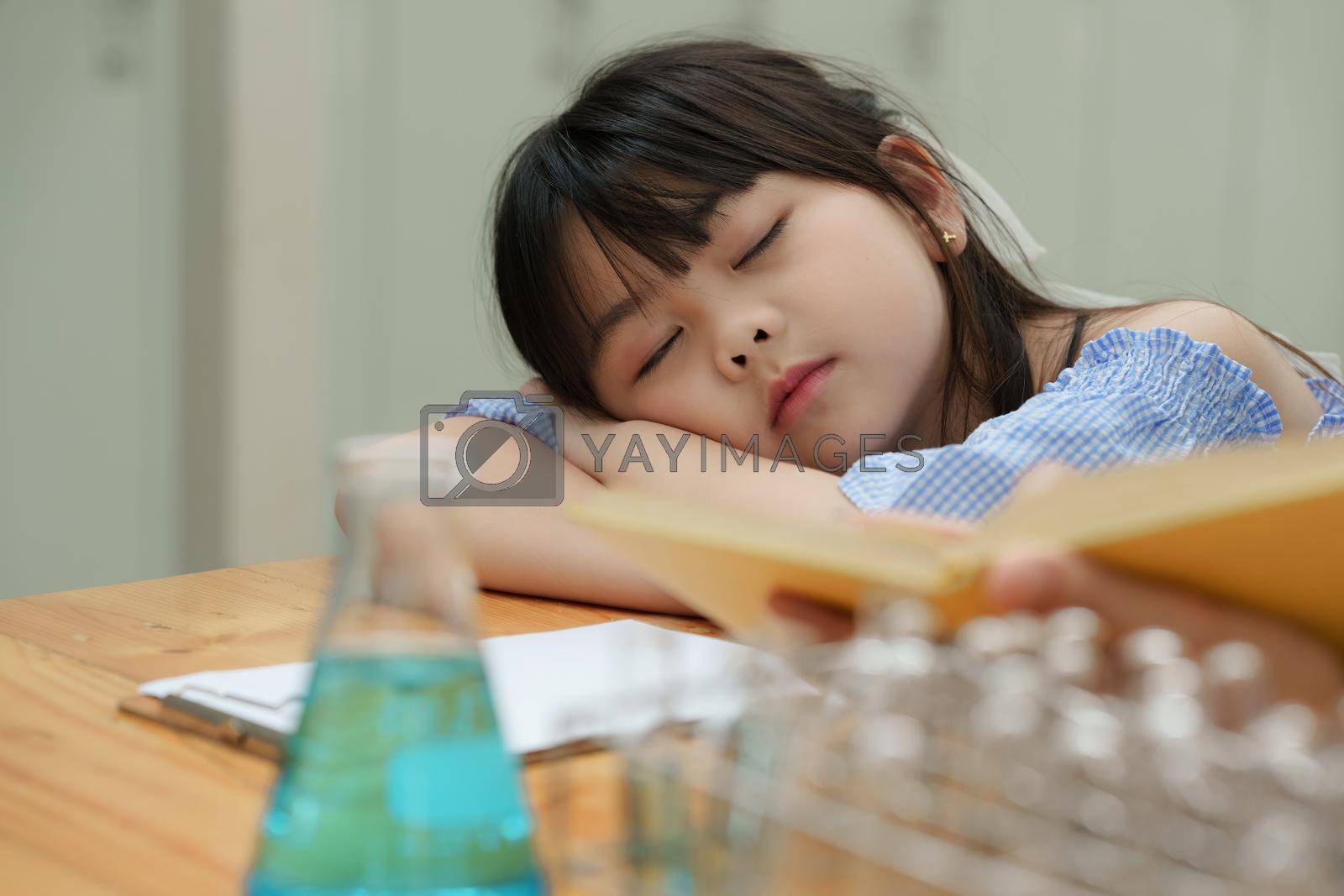 Royalty free image of Kid sleeping while doing science experiments. Education science concept by itchaznong