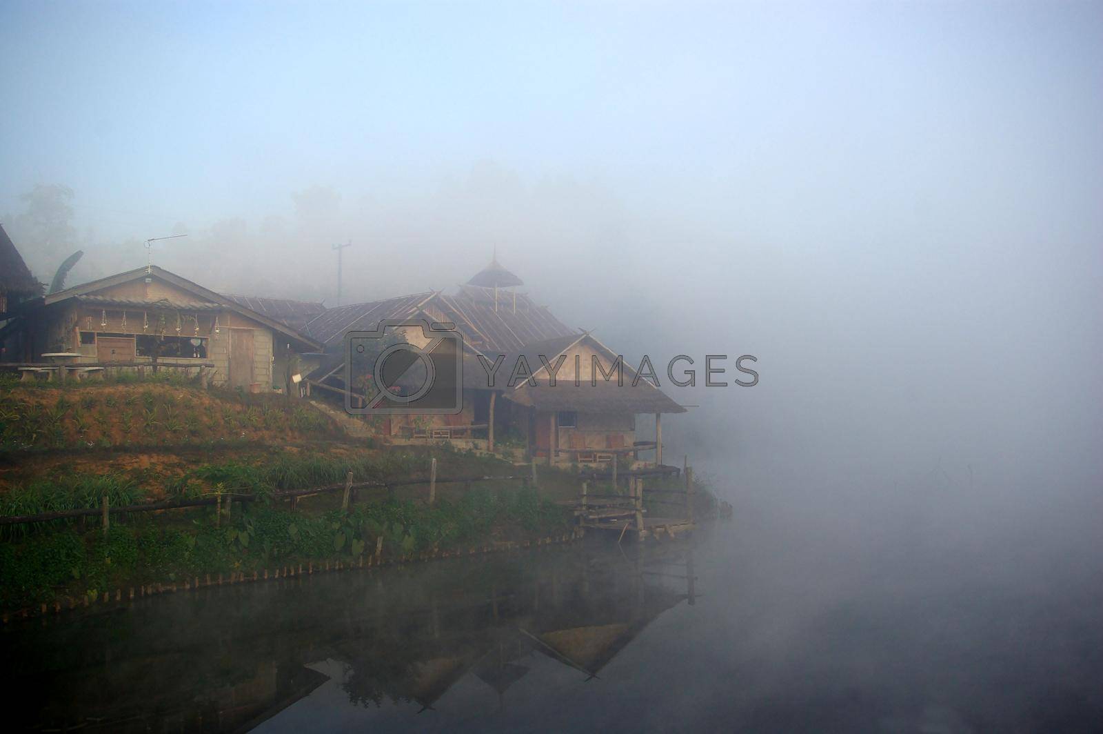 Royalty free image of wooden house in the morning mist and the lake view in the countryside by Satakorn
