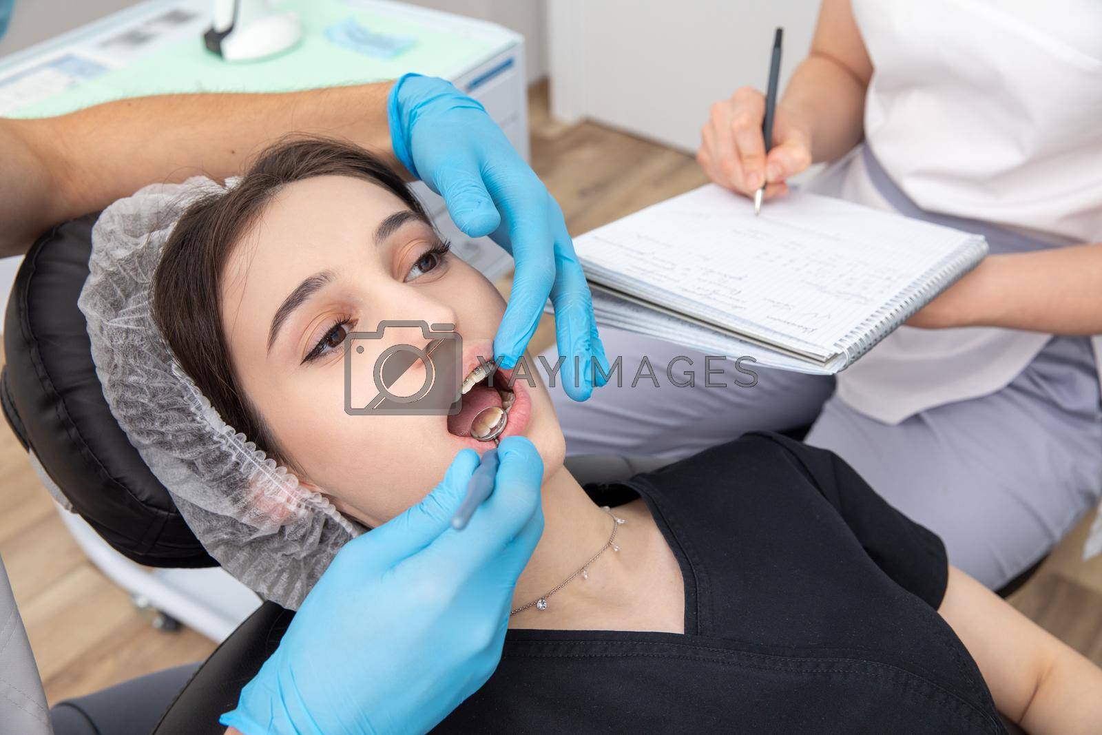 Dentist examining patient teeth with mirror in dentist clinic. Having dental checkup