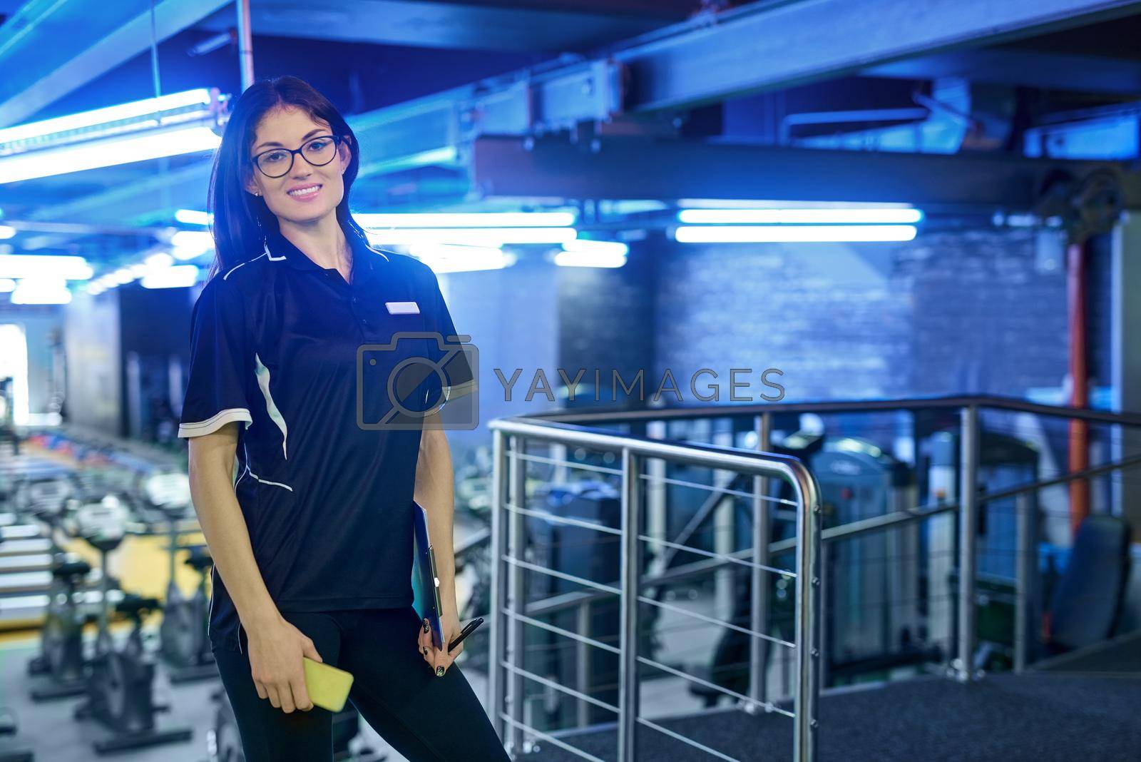 Royalty free image of Im here to help. Portrait of a young personal trainer standing in the gym. by YuriArcurs