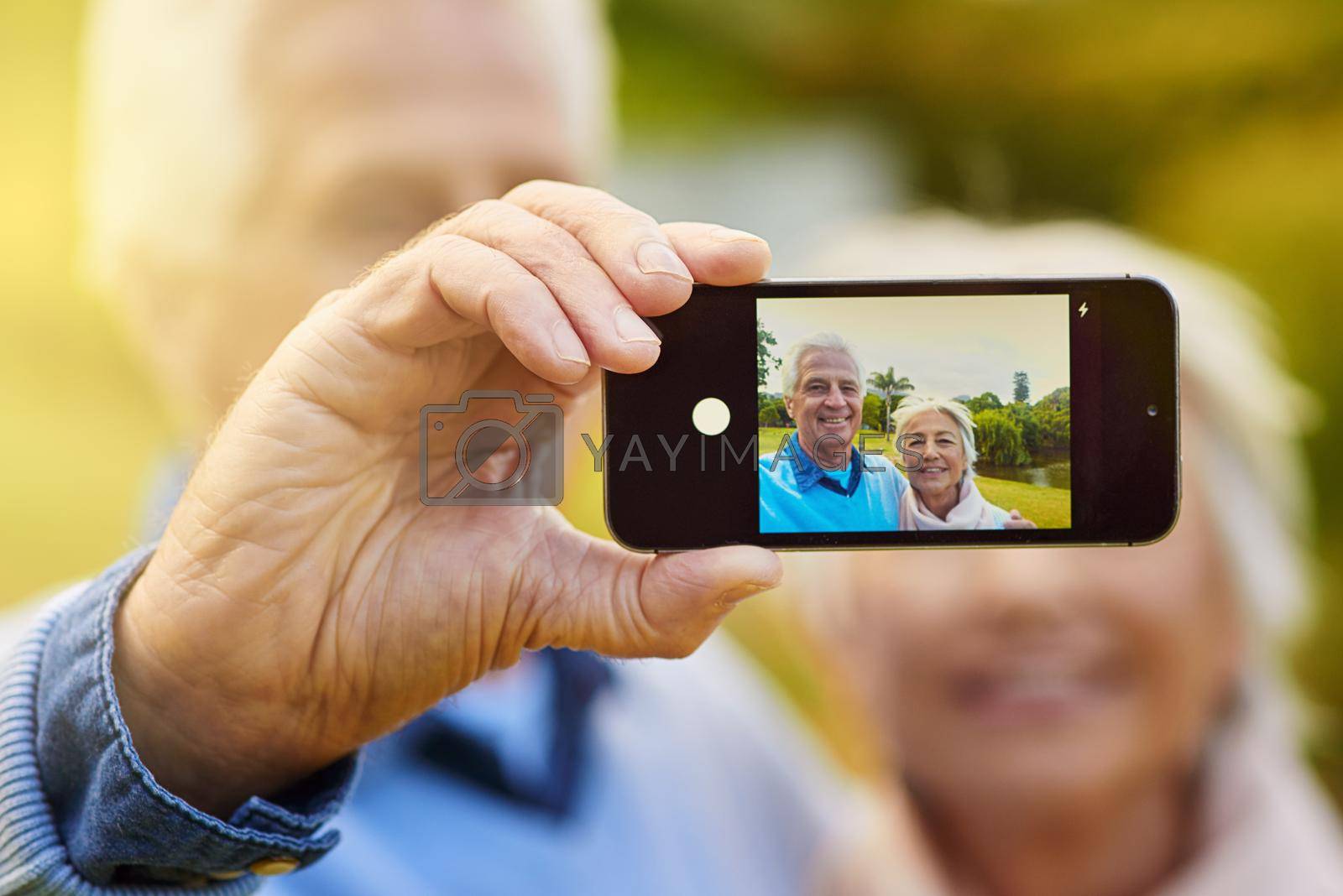 Royalty free image of Well add this to our photo album. a senior couple taking a photo together in a park. by YuriArcurs