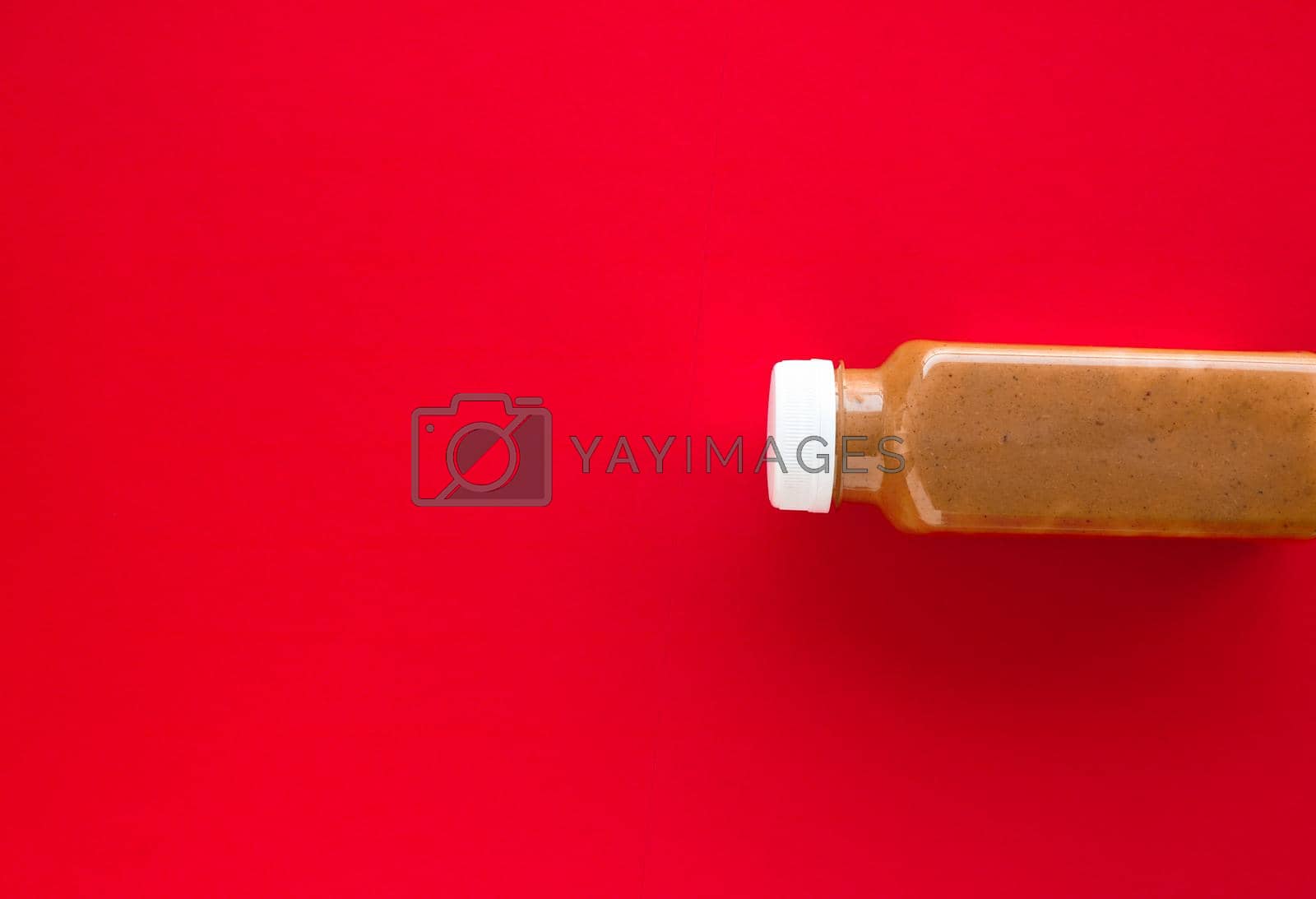Royalty free image of Chocolate banana smoothie bottle on red, flatlay by Anneleven