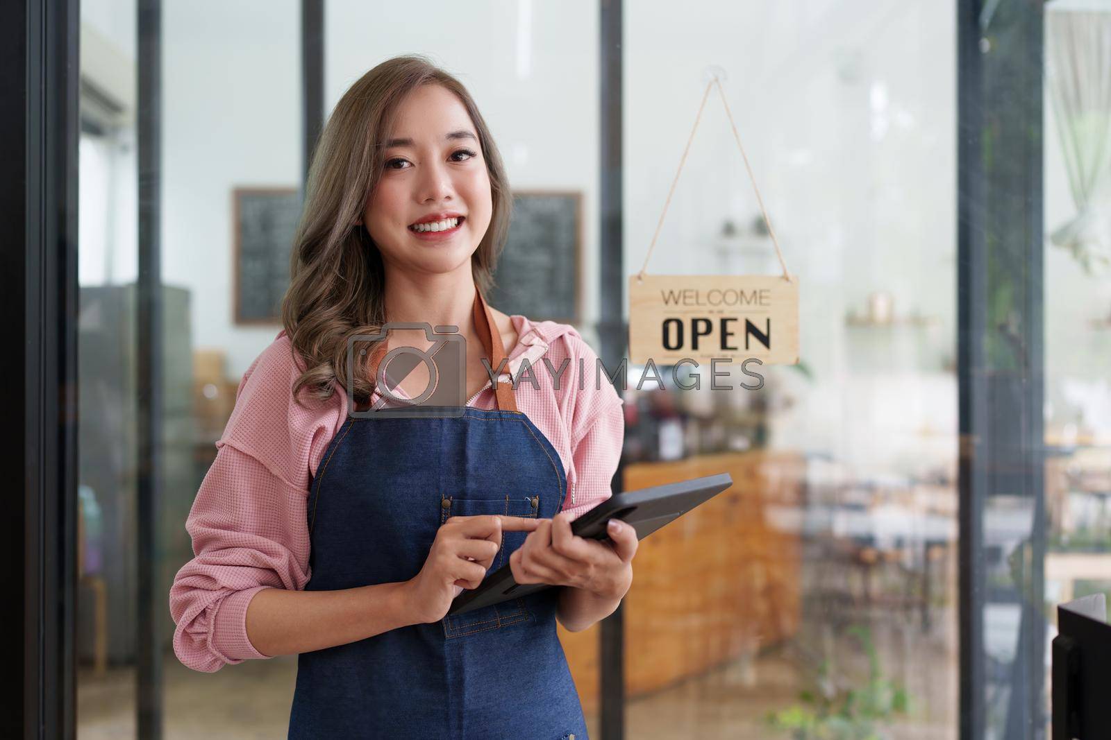 Royalty free image of Asian Barista cafe owner smile while cafe open. SME entrepreneur seller business concept by itchaznong