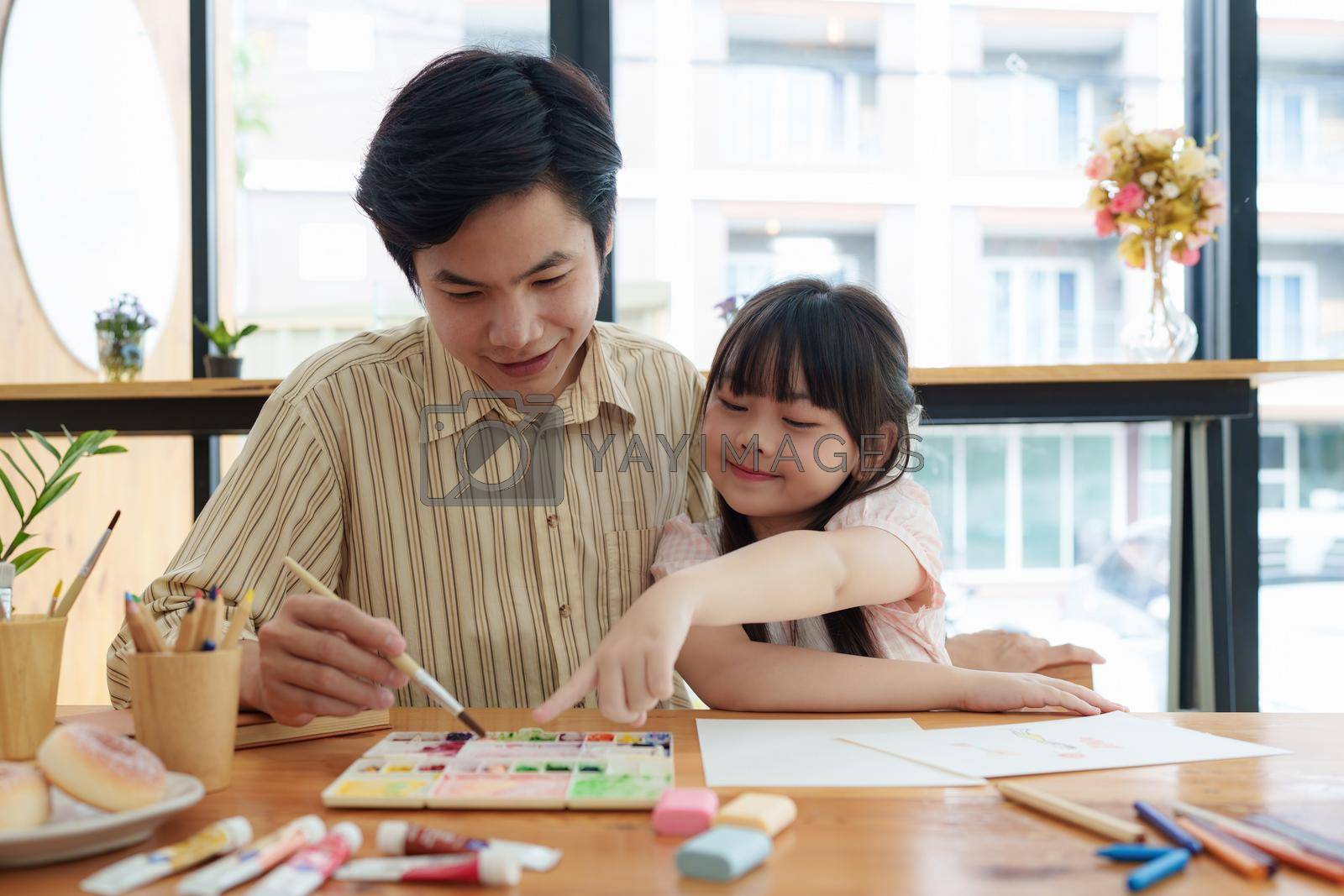 Royalty free image of A happy kid and this father painting at home. Handmade skills training by itchaznong