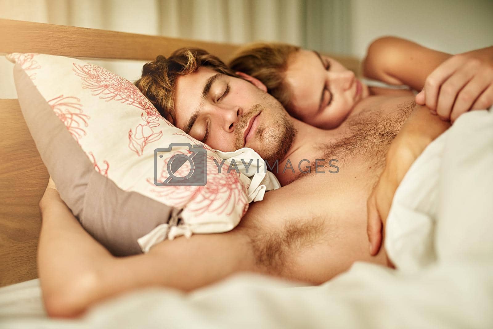 Royalty free image of Weekend time is cuddle time. a young couple asleep in bed at home. by YuriArcurs