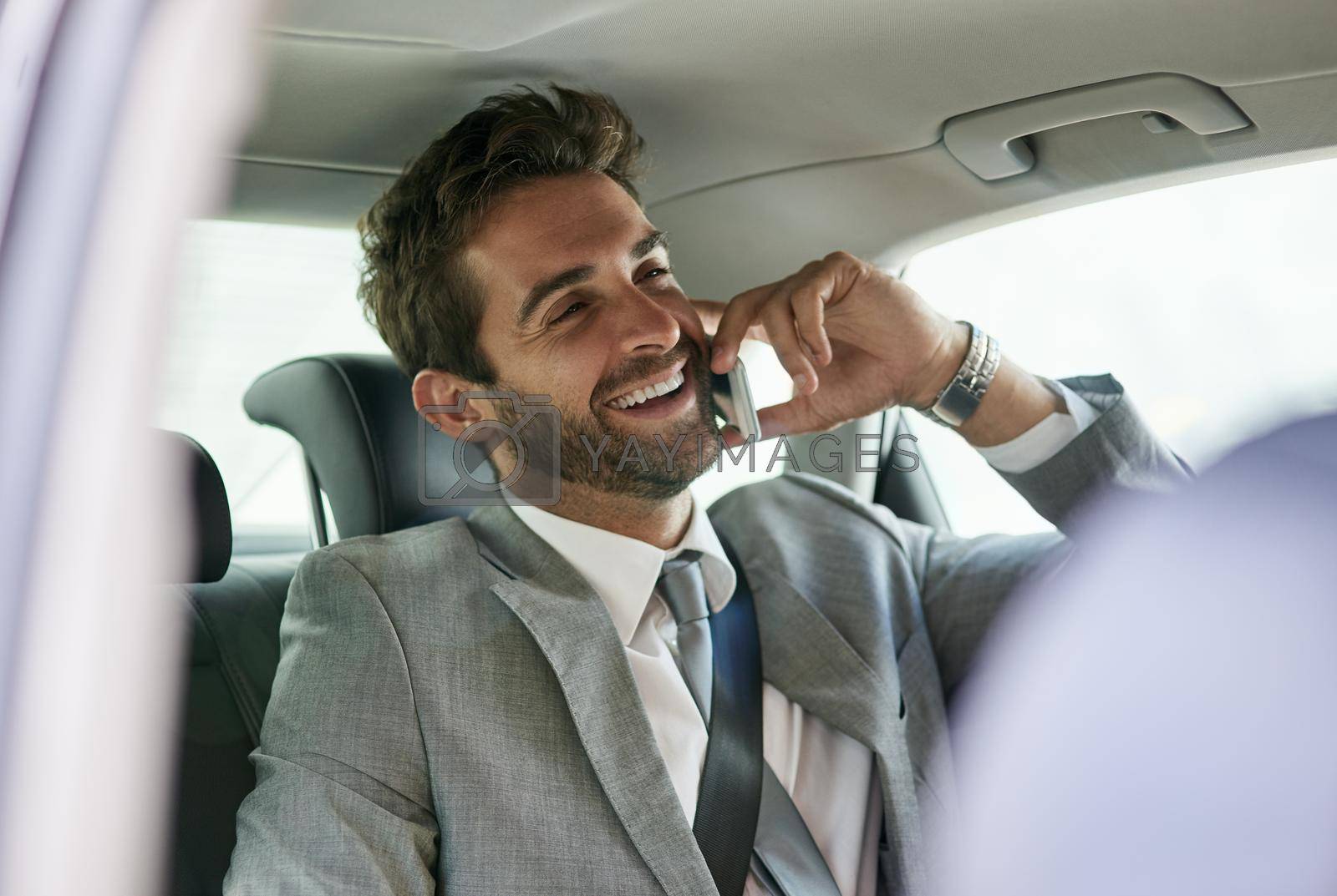 Royalty free image of Hes a businessman on the move. a handsome young businessman talking on a cellphone in the back seat of a car. by YuriArcurs