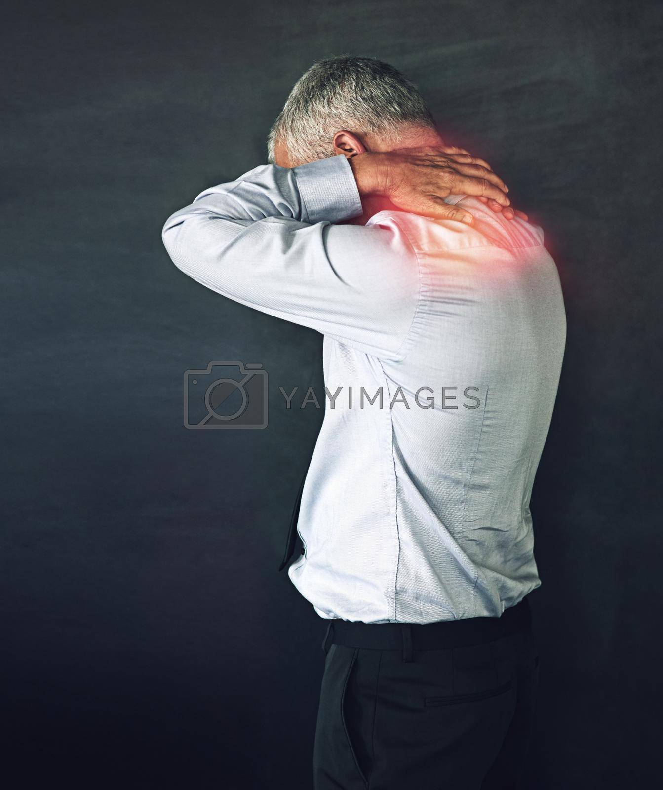 Royalty free image of When work stress becomes physical. Studio shot of a mature man experiencing neck ache against a black background. by YuriArcurs