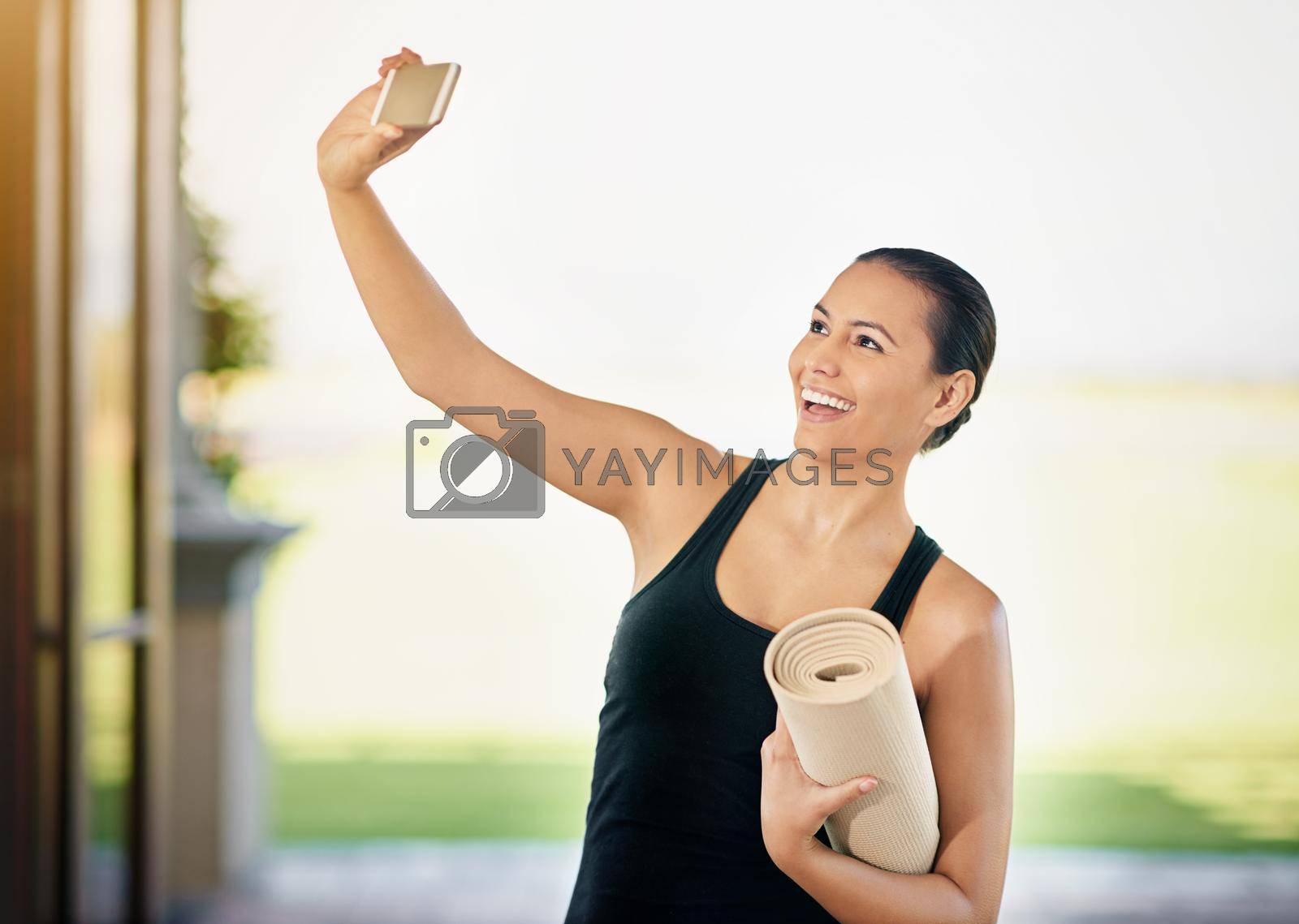 Royalty free image of Yoga selfie. a young woman taking a selfie while carrying her yoga mat. by YuriArcurs