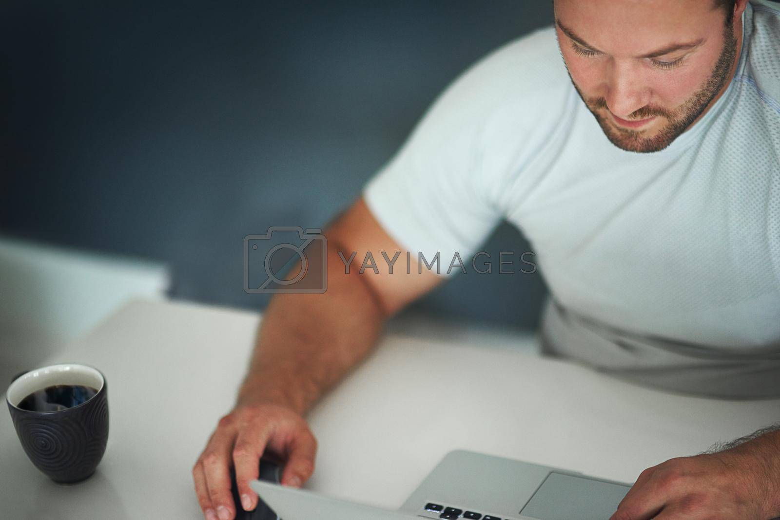 Royalty free image of Adding some content to his blog. a young man working on his laptop. by YuriArcurs