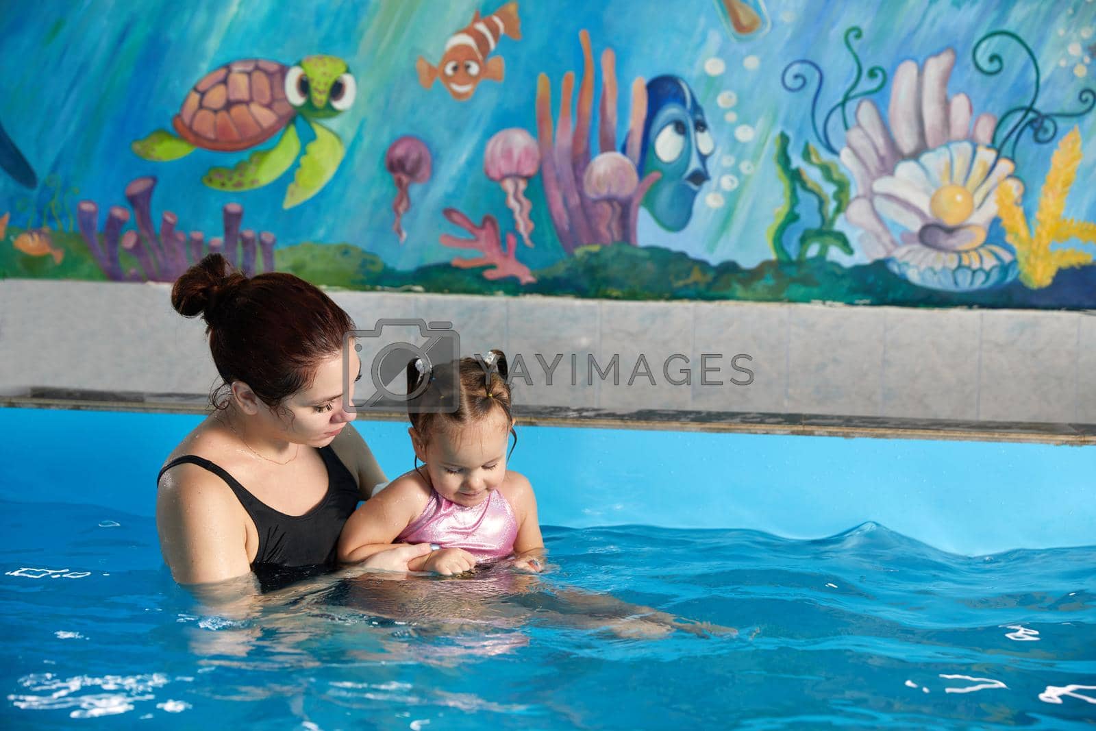 Royalty free image of Little child learning to swim in pool with teacher by Mariakray
