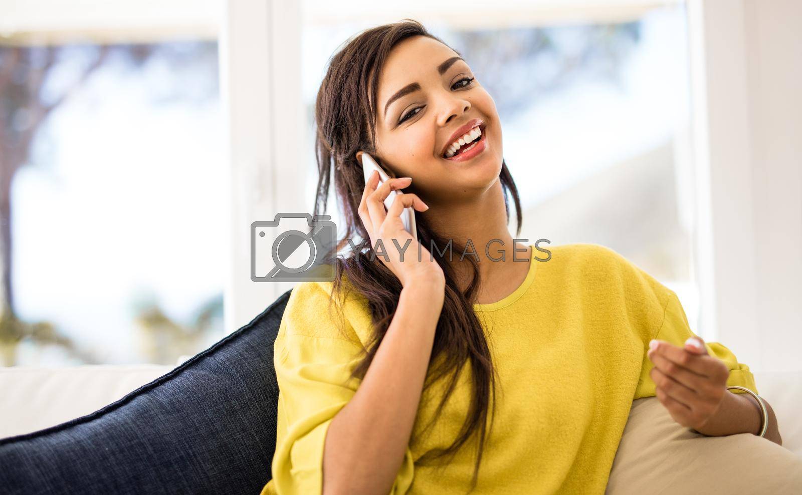 Royalty free image of Do you have time to chat. a young woman talking on her cellphone at home. by YuriArcurs