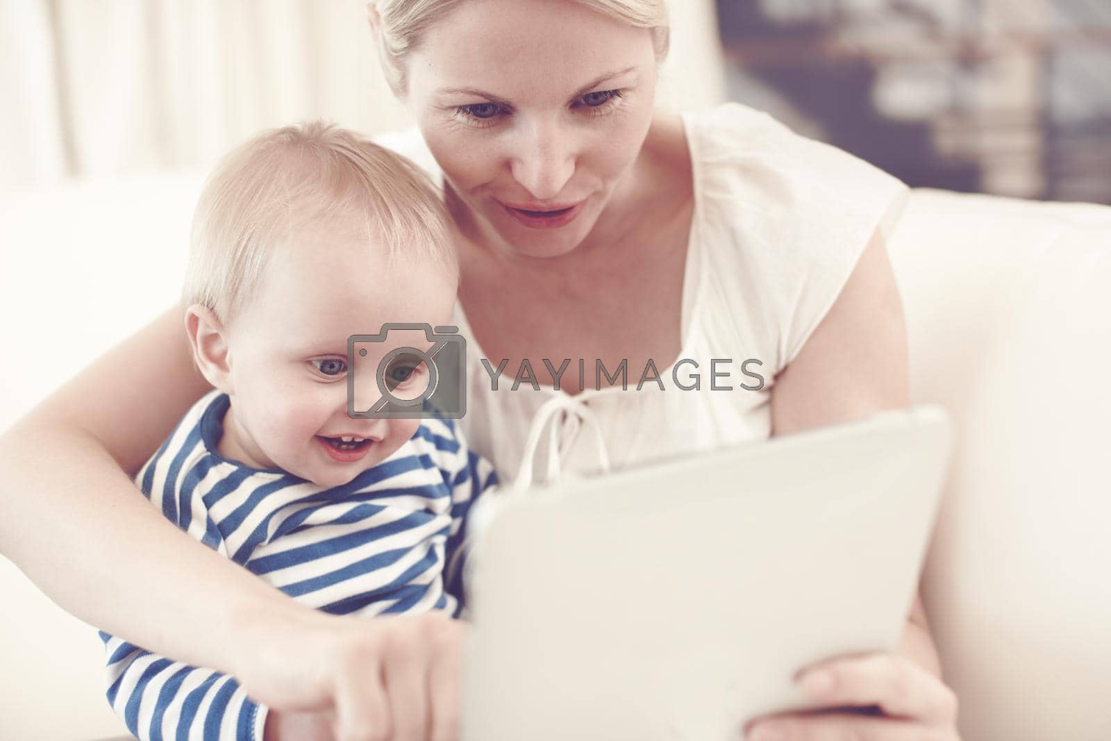 Royalty free image of Look at this one. An attractive young mother showing her curious baby a touchscreen tablet. by YuriArcurs