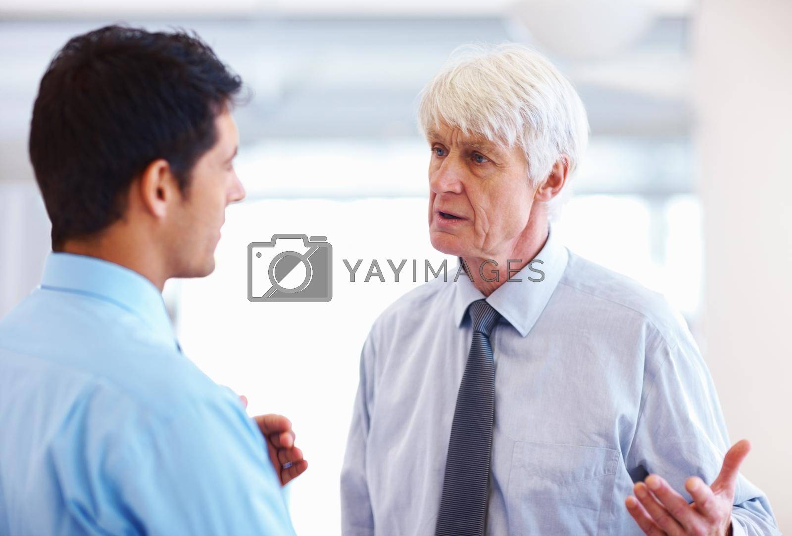 Royalty free image of Business men in serious conversation. Portrait of successful business men having serious conversation at office. by YuriArcurs