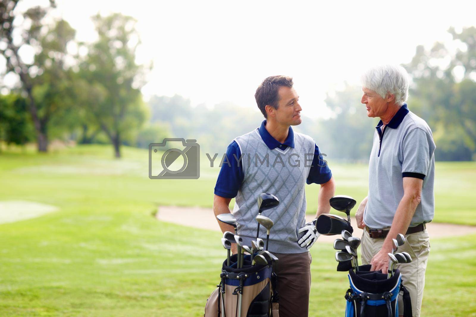 Two golfers in discussion. Father and son standing on golf course and discussing with each other