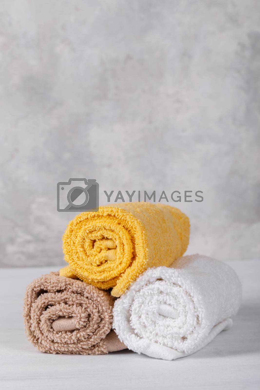 Spa composition with white, pink and brown soft rolled cotton towels, copy space