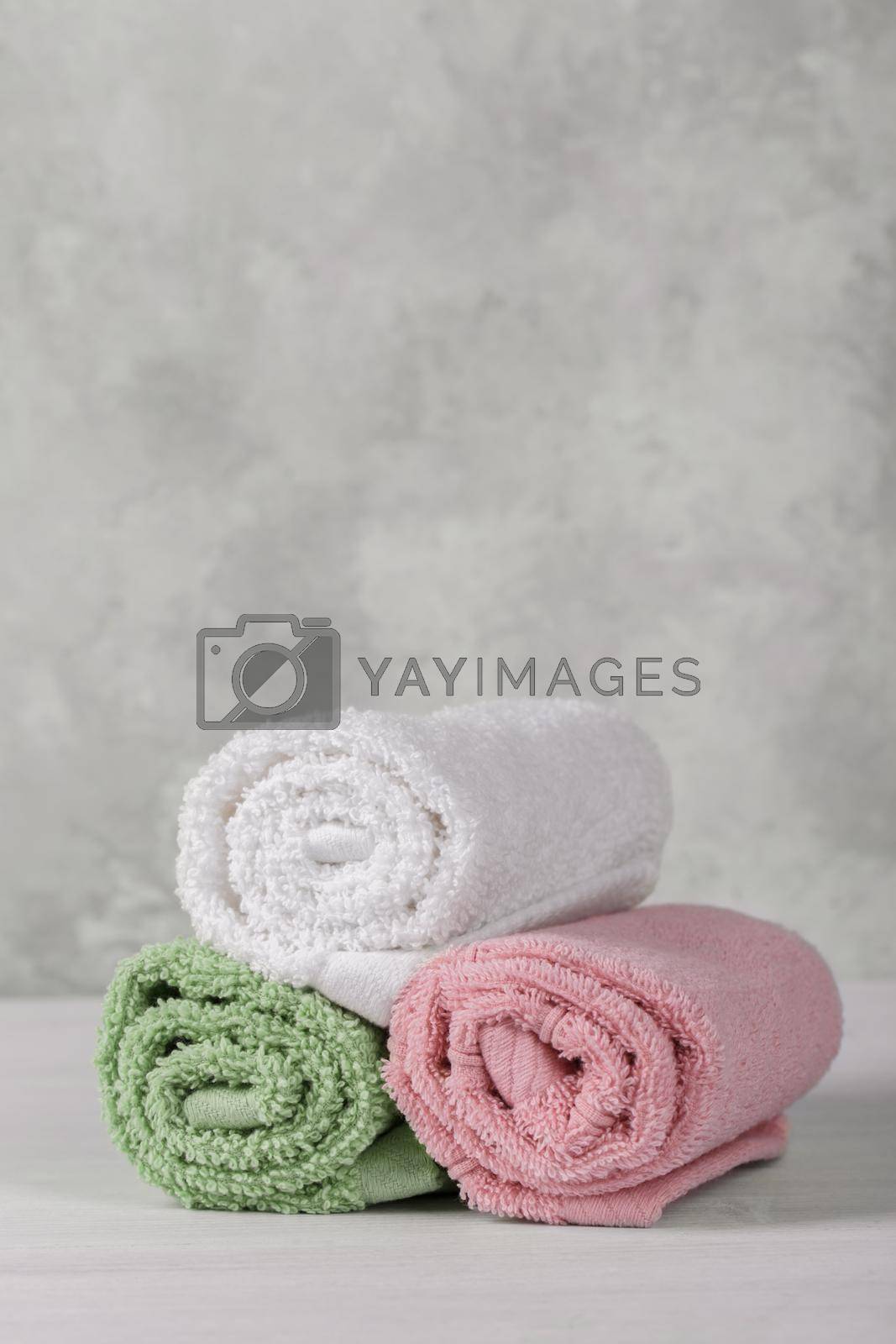 Spa composition with white, pink and green soft rolled cotton towels, copy space vertical