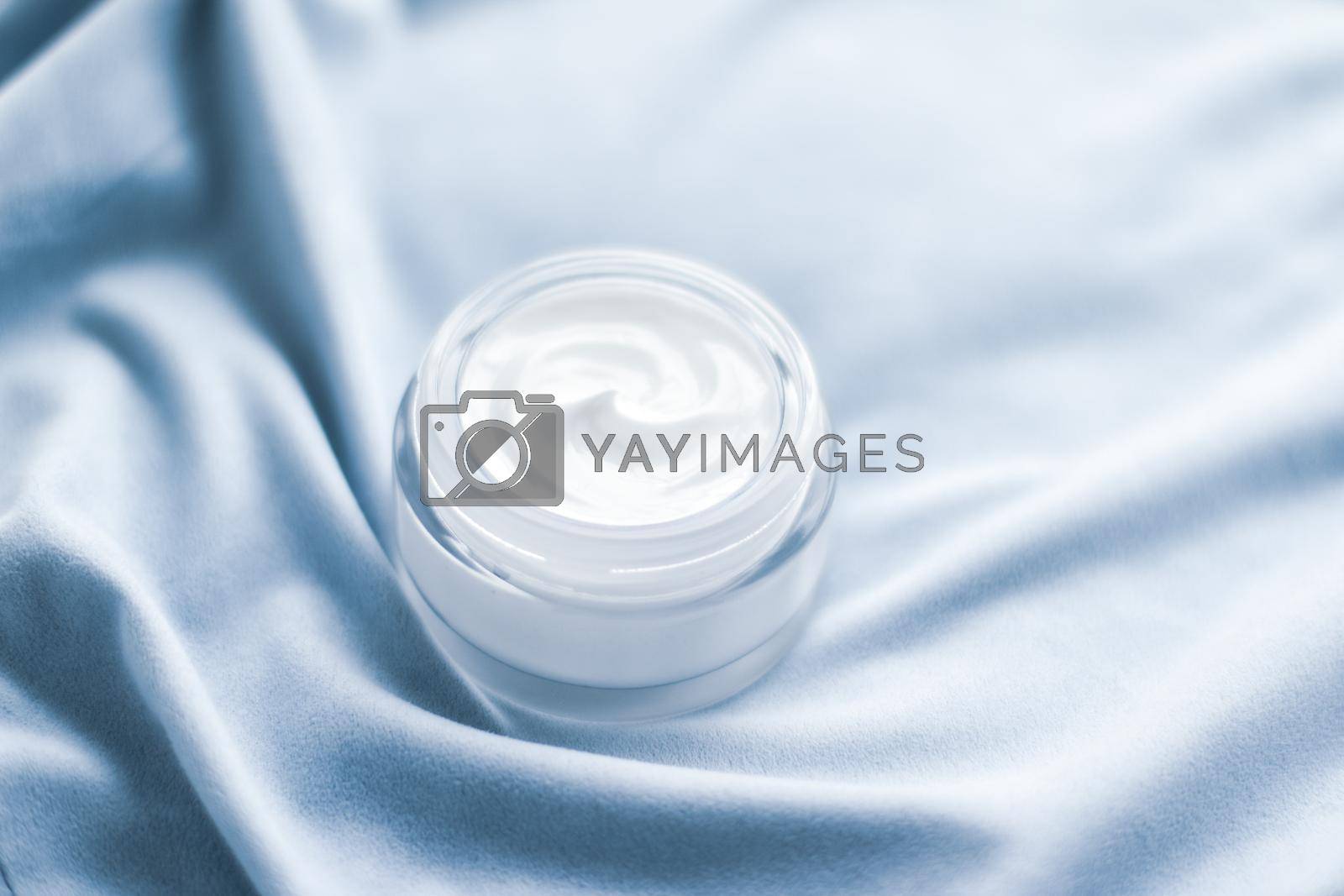 Royalty free image of Luxury face cream jar on blue silk by Anneleven