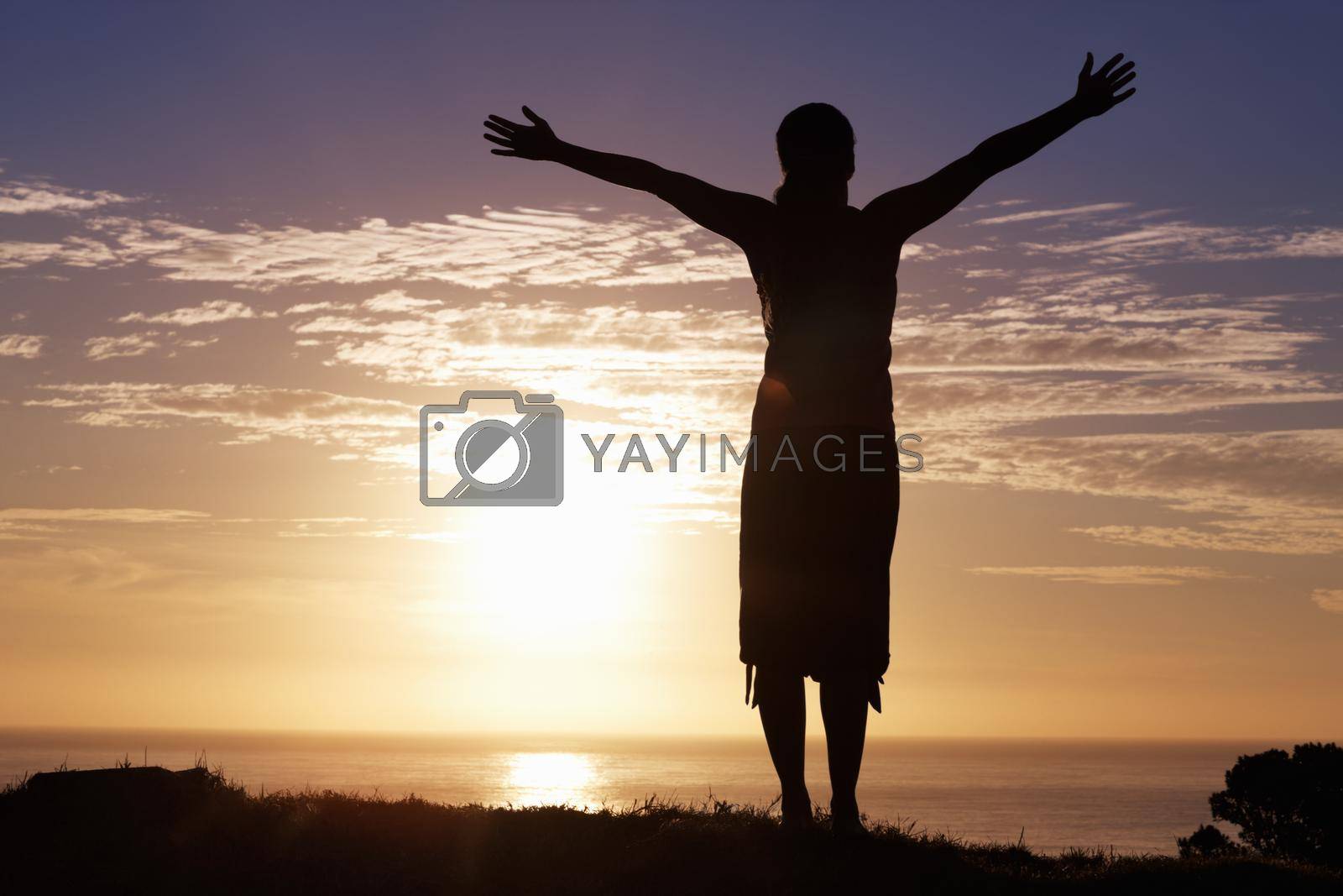 Royalty free image of Enjoying life. Silhouette of a woman standing by sunrise with arms outstretched. by YuriArcurs