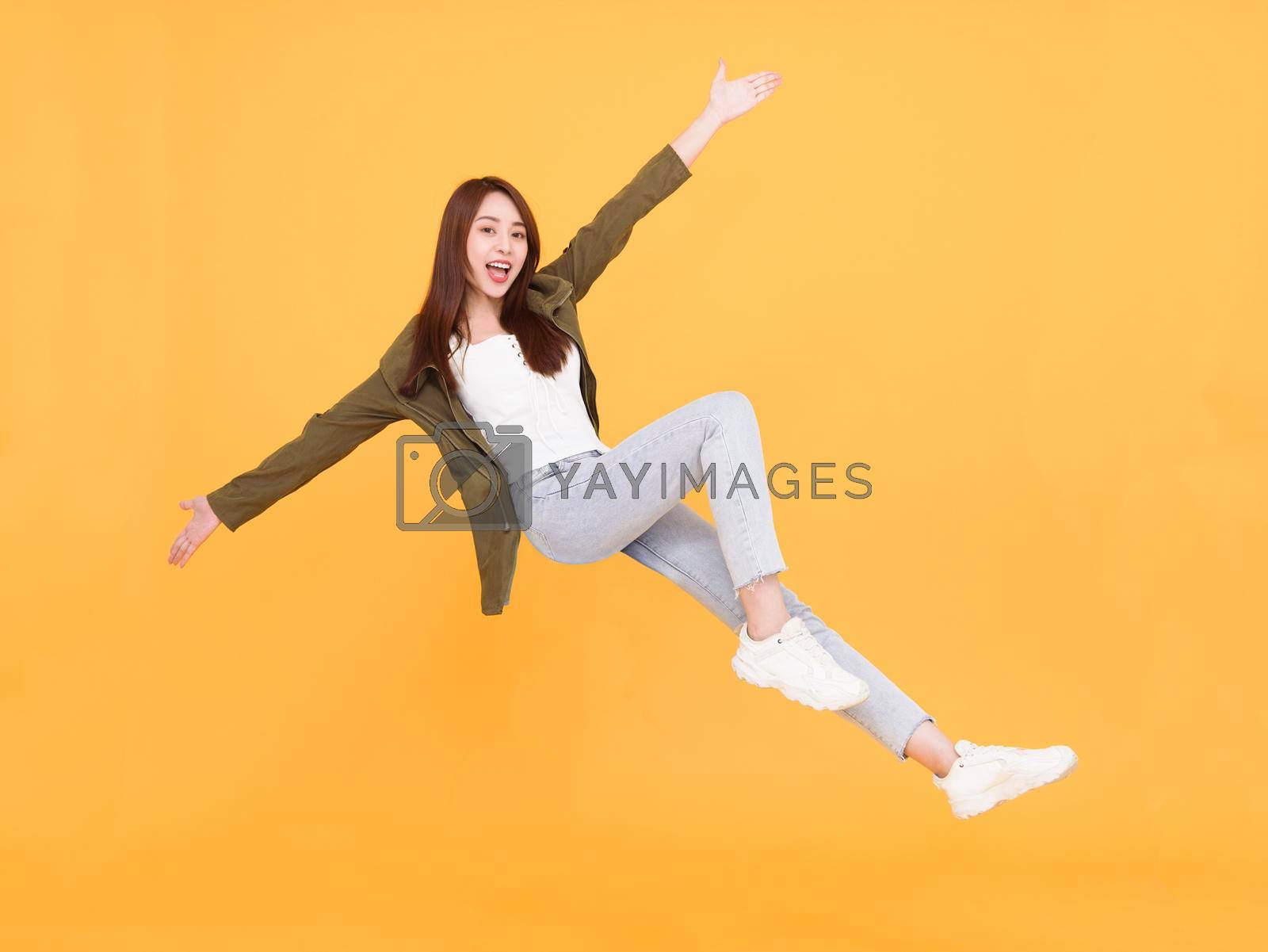 Royalty free image of Happy  young woman  jumping and dancing  isolated over yellow background by tomwang