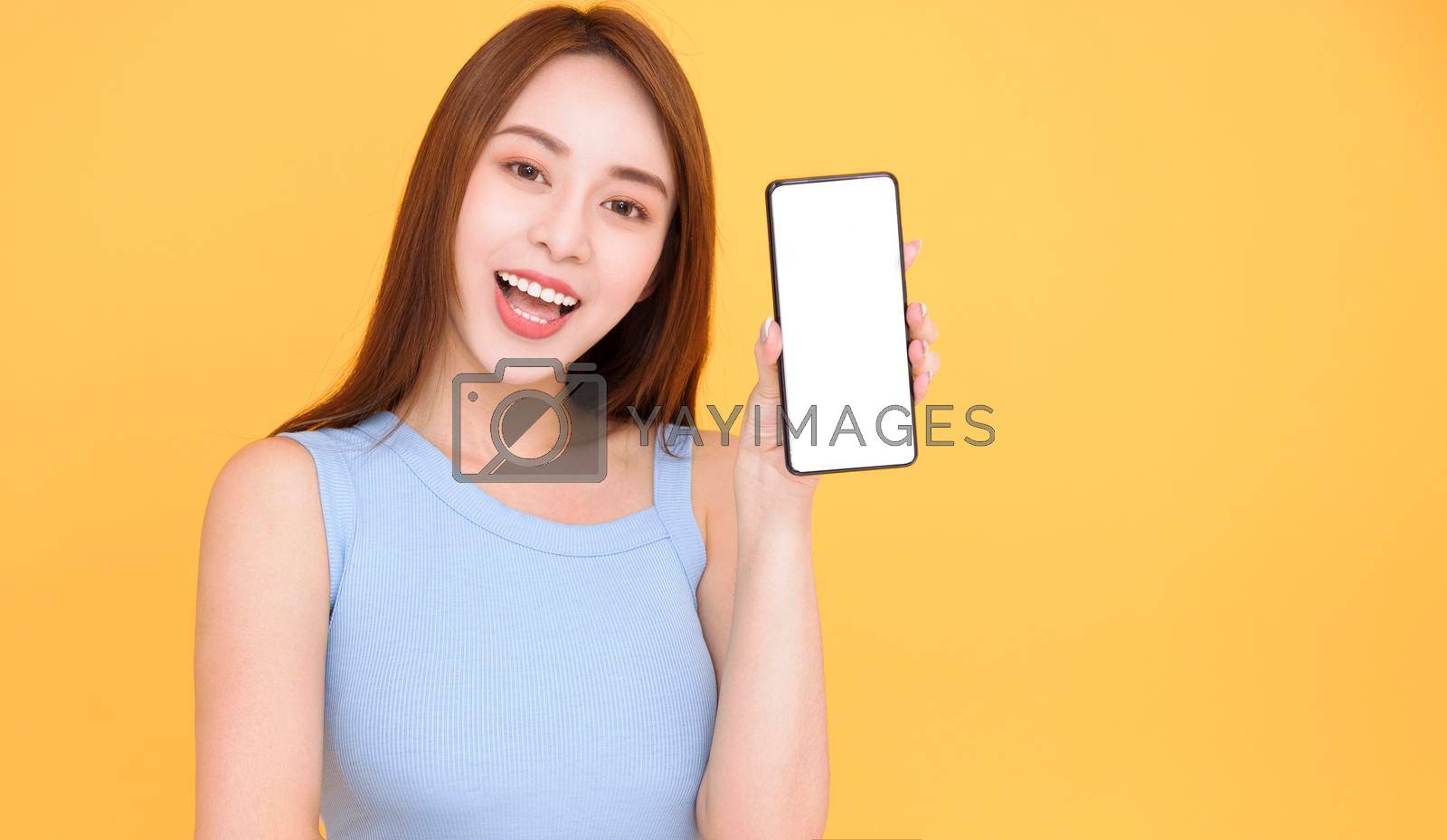 Royalty free image of Happy asian woman showing mobile phone blank screen on yellow background by tomwang