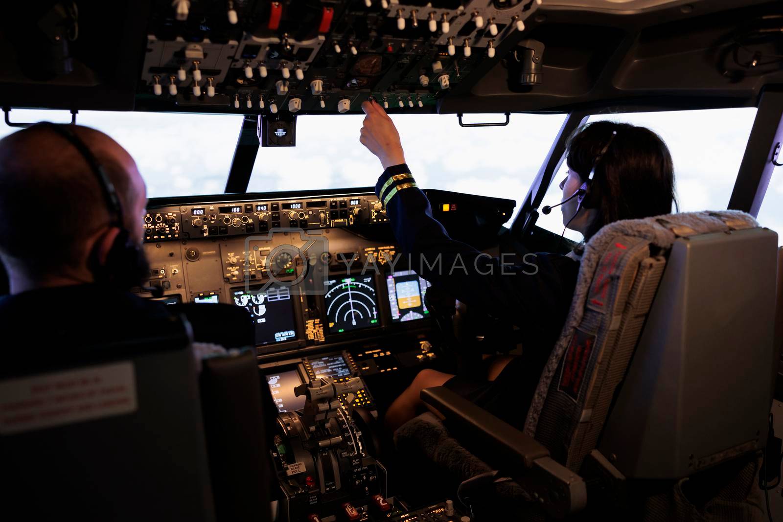 Royalty free image of Team of aircrew member and captain using power switch on cockpit dashboard by DCStudio