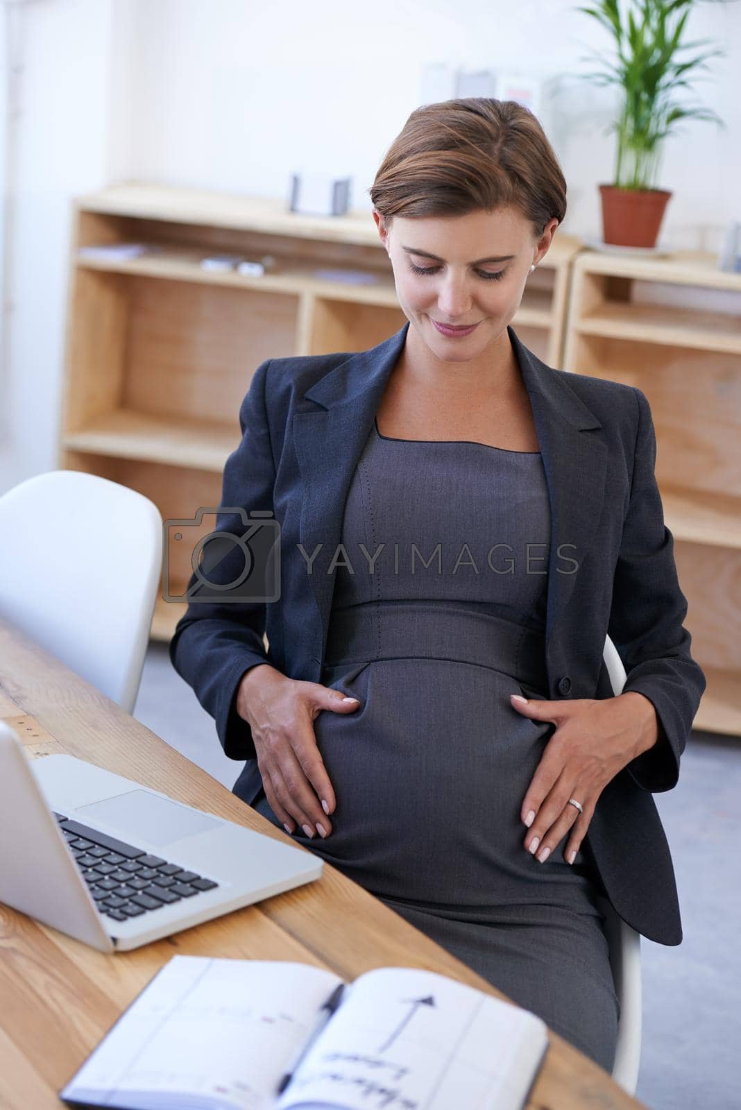 Royalty free image of The movement of life inside you, theres no better feeling. a business woman touching her pregnant belly. by YuriArcurs