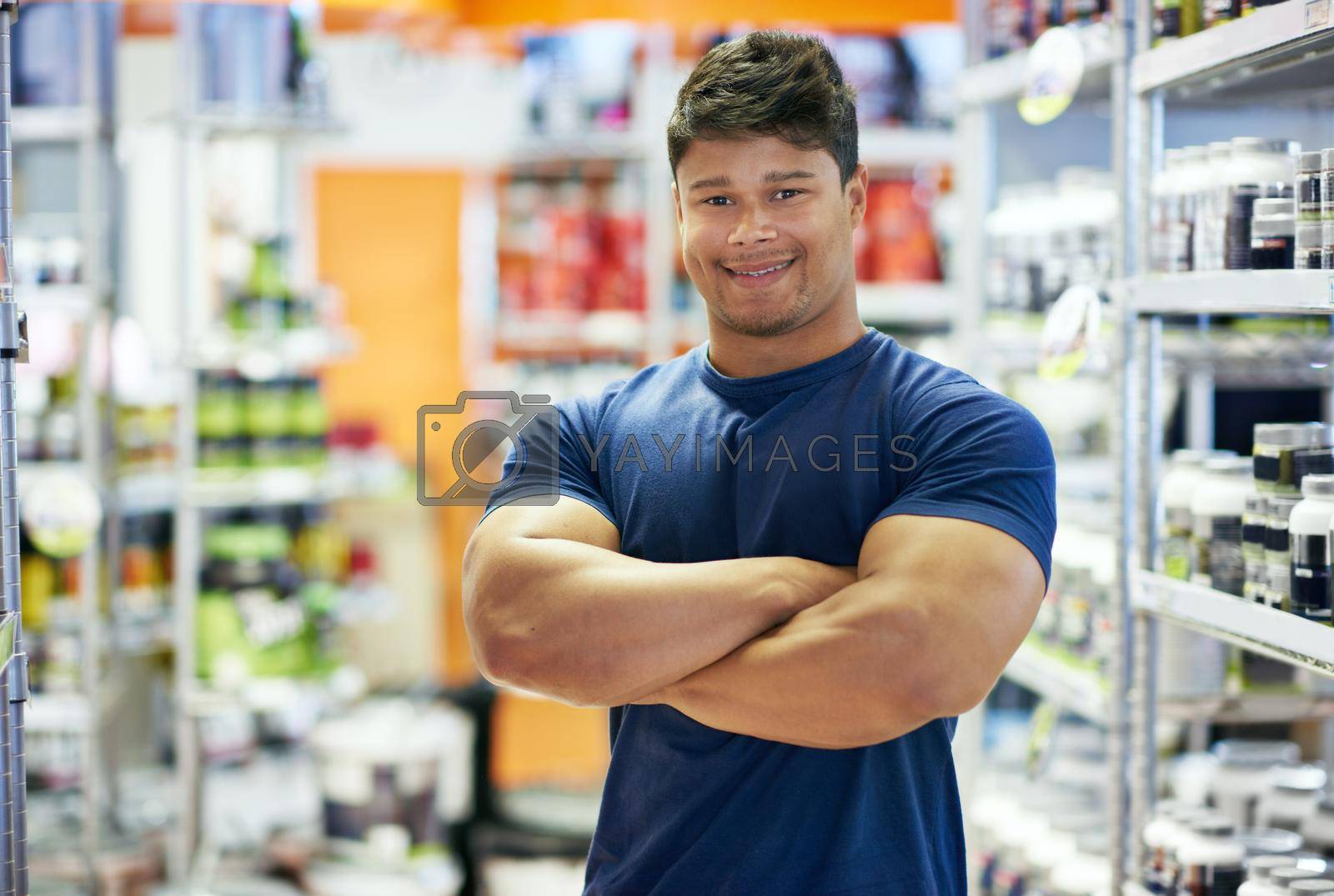 Royalty free image of I built these myself. a muscular young man in the supplement section of a pharmacy. by YuriArcurs